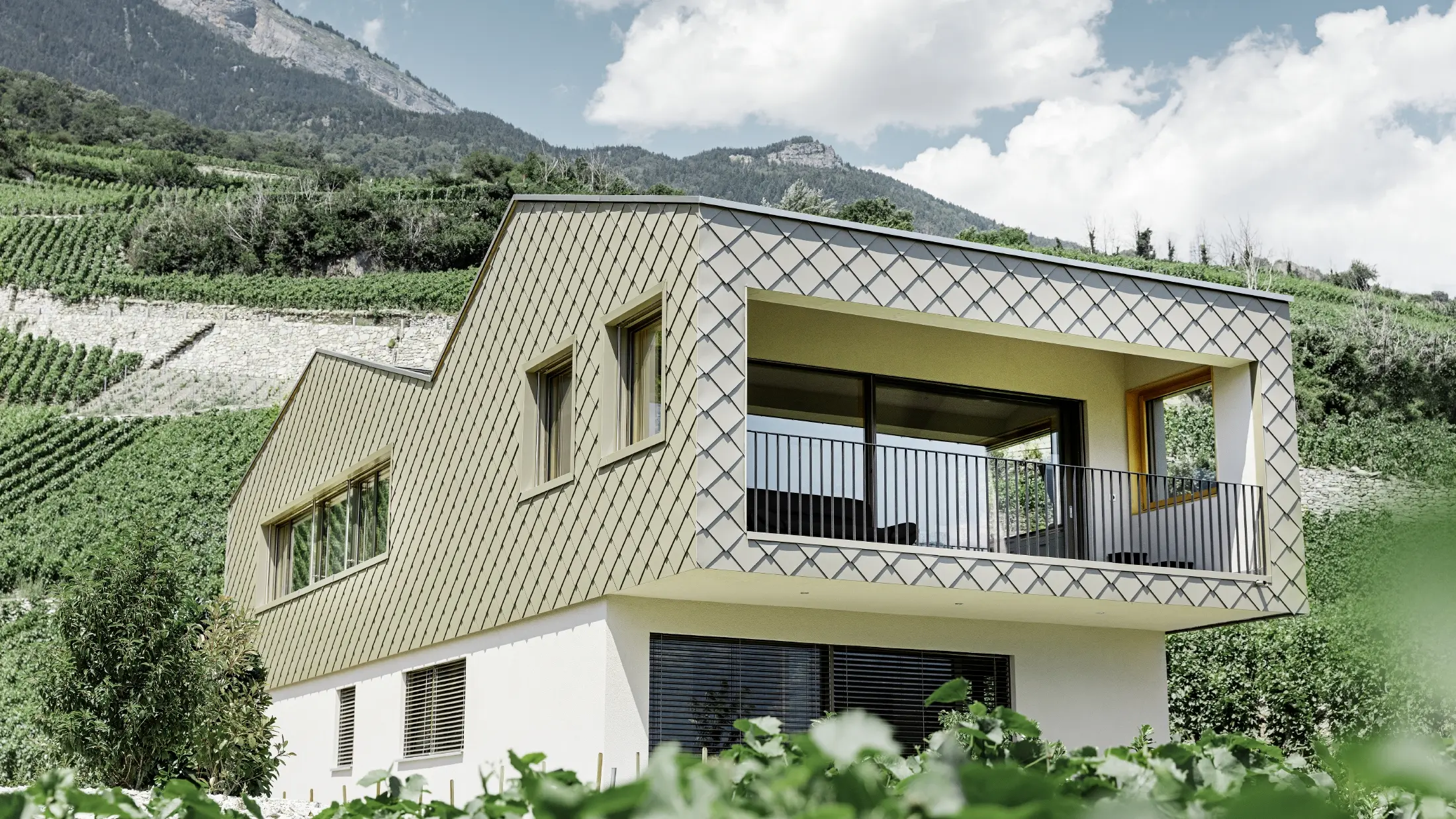Maison individuelle moderne au cœur des vignobles de la vallée du Rhône avec quatre pentes de toit et grand balcon couvert — Façade habillée de losanges PREFA de couleur bronze
