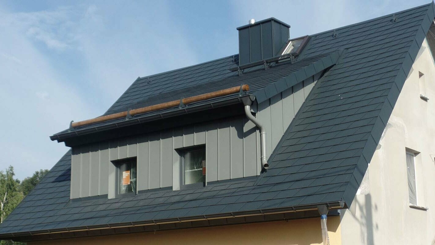 Bâtiment avec toit à deux pans et lucarne rampante, rénové à l’aide de bardeaux de toiture PREFA
