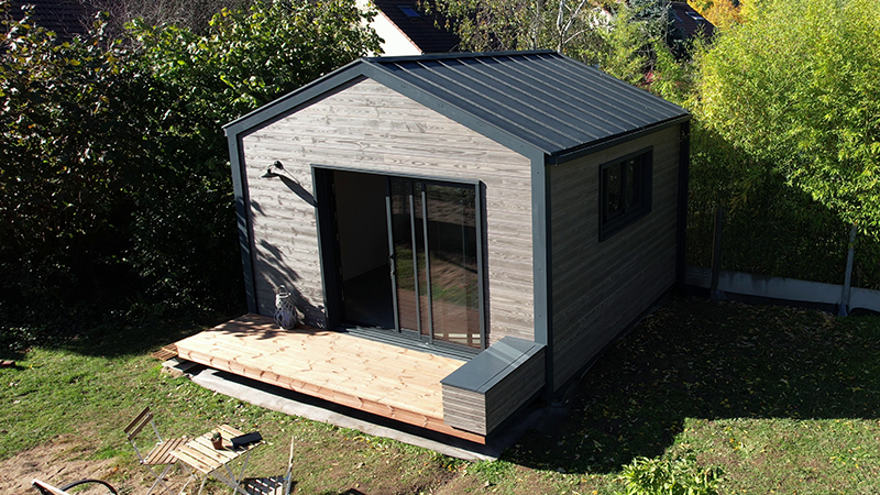 Vue surélevée du lodge dont la toiture est en aluminium PREFA dans la teinte anthracite, tout comme la gouttière et le tuyau de descente. 