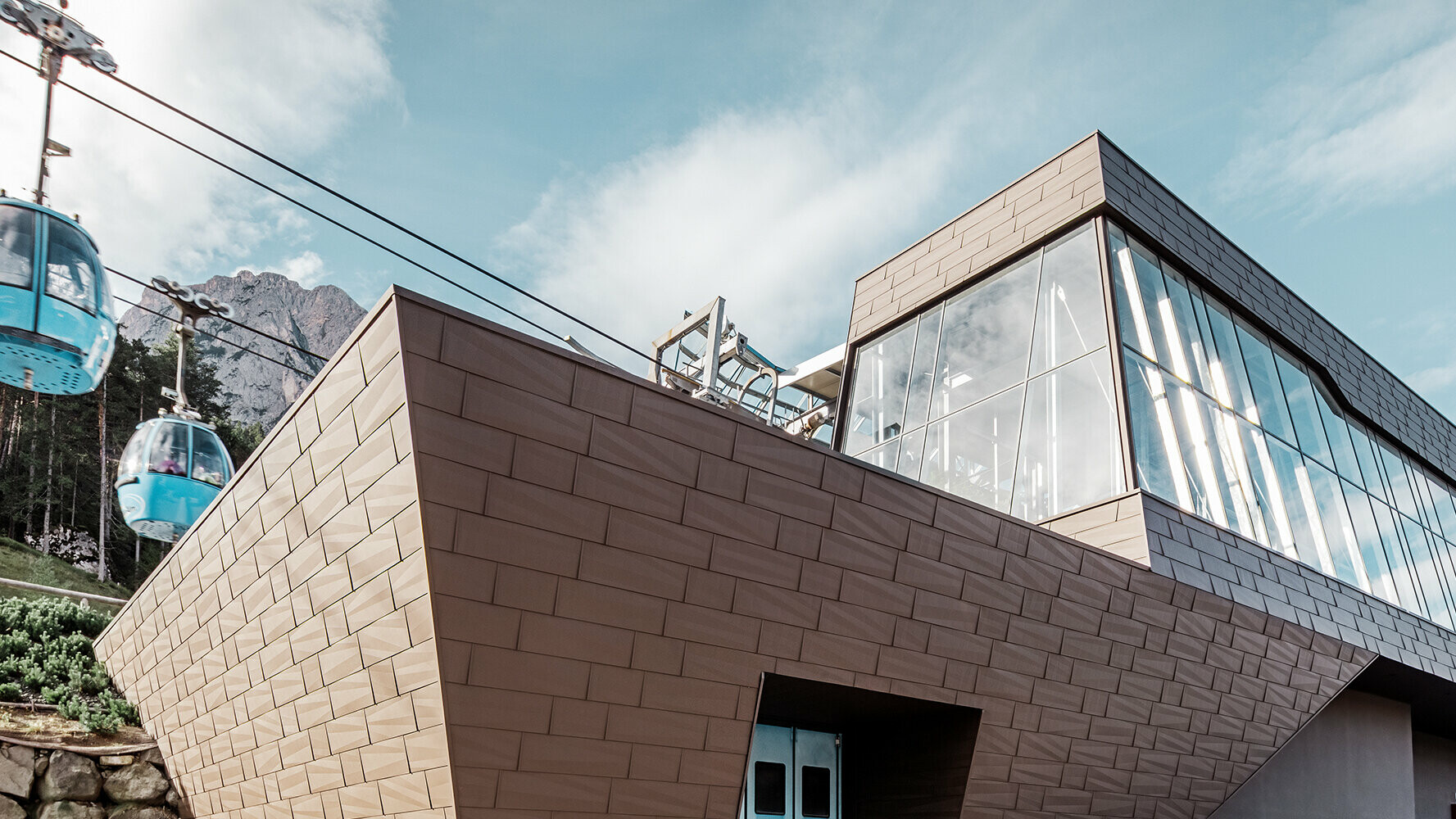 Gare de départ d’une télécabine dans le Tyrol du Sud avec revêtements de toit et de façade PREFA modernes de couleur brune.