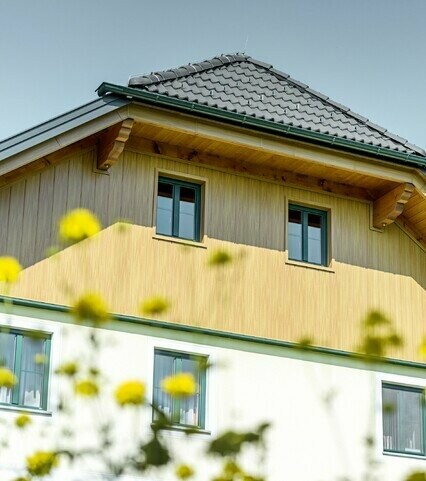Revêtement de pignon avec panneaux en aluminium de PREFA imitation (chêne naturel) ; les Sidings sont posés à la verticale avec revêtement de la sous-face de toiture