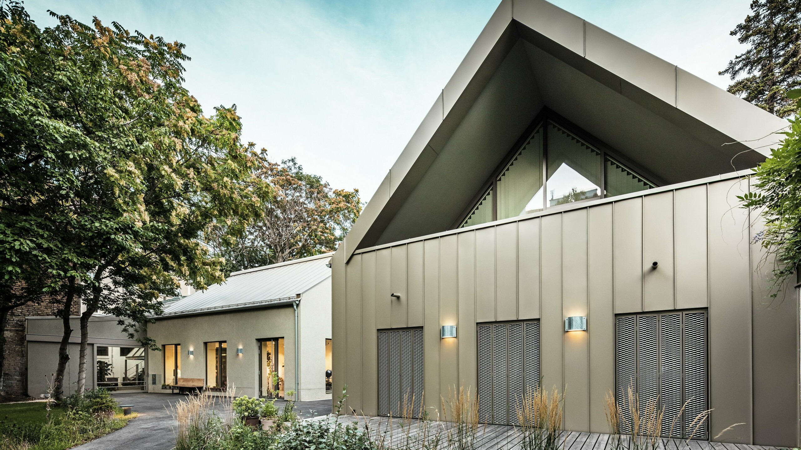 Vue de face du Studio Comploj à Vienne avec une façade en aluminium PREFALZ en P.10 bronze Prefa. L'atelier de soufflage de verre moderne allie artisanat et architecture contemporaine.