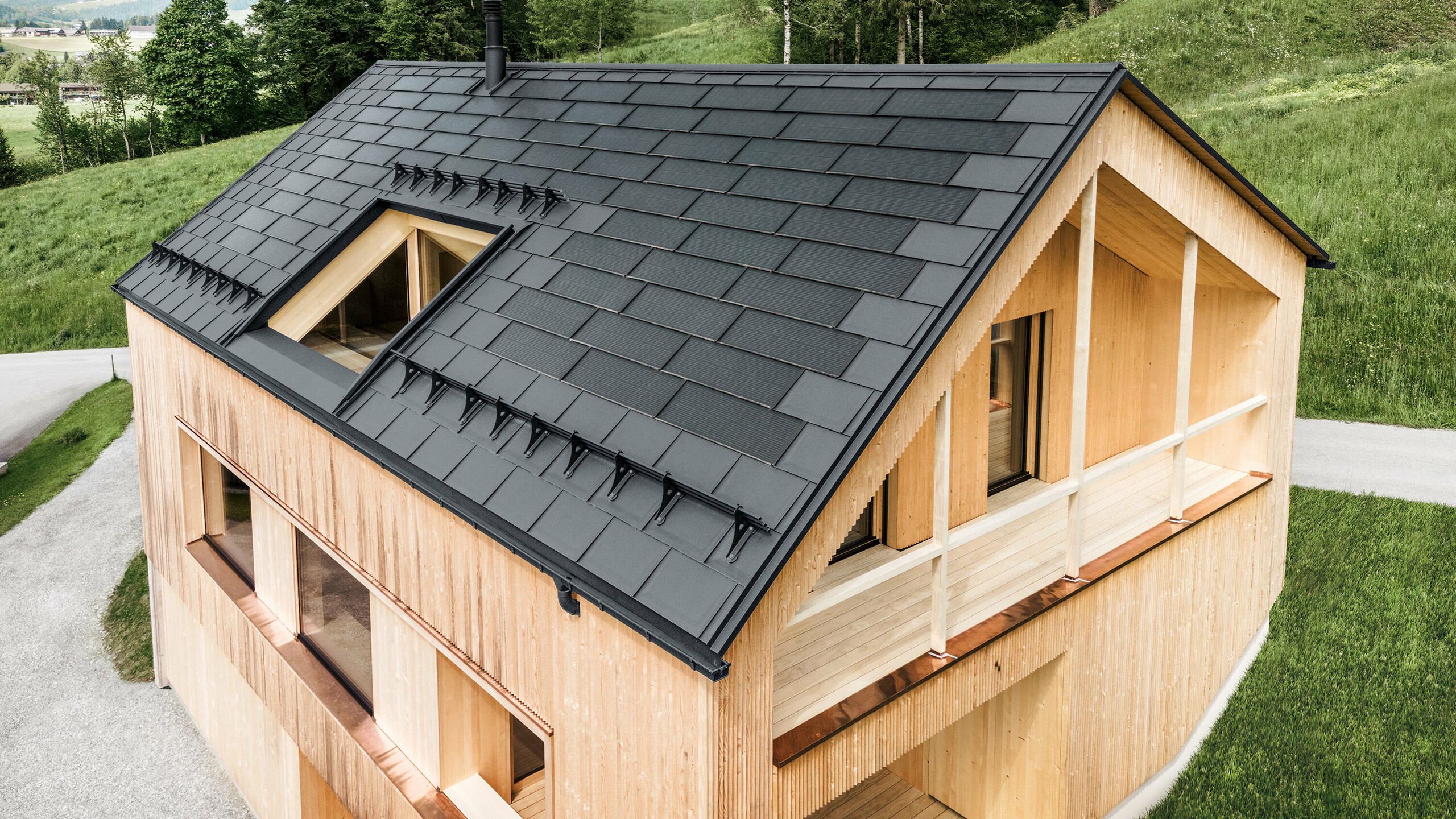 Maison individuelle dans la localité autrichienne d'Egg avec le panneau solaire de toiture PREFA et le panneau de toiture R.16 en gris foncé, combinés à une façade en bois