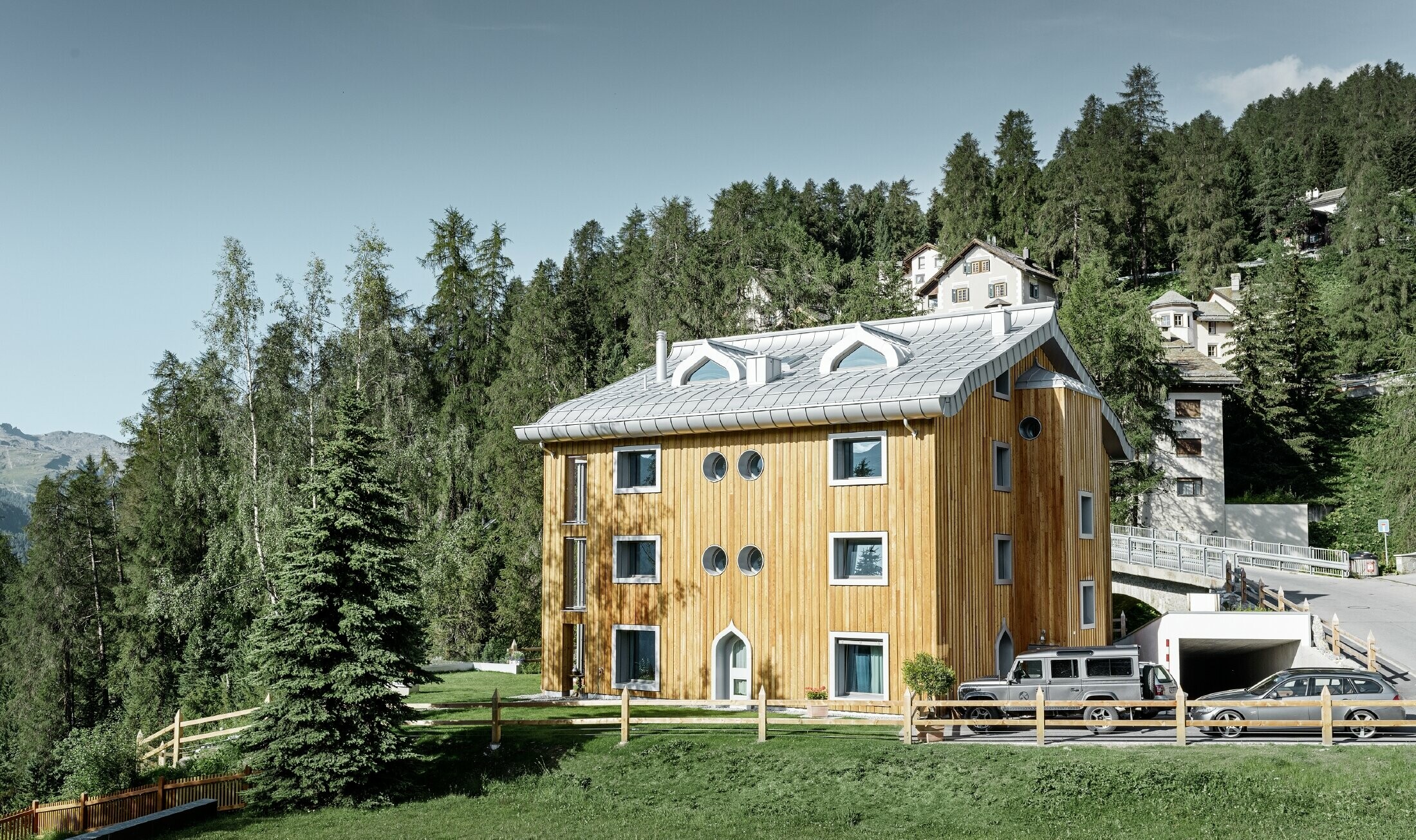 Complexe résidentiel de St. Moritz à la façade en bois — Toiture en aluminium PREFA de couleur argent métallisé avec avant-toit curviligne
