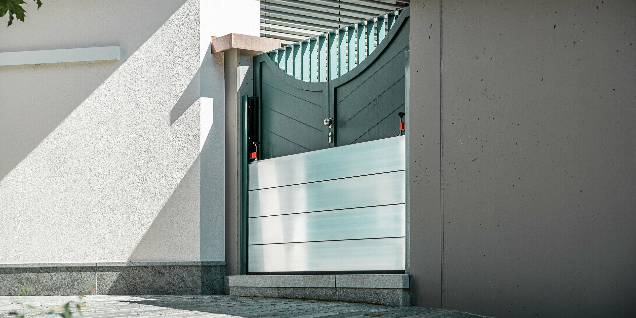 Gros plan sur un système de protection contre les crues PREFA installé sur le portail d'une maison individuelle à Schwaz, au Tyrol. Les batardeaux en aluminium sont insérés dans des profilés de fixation latéraux et protègent efficacement l'entrée des infiltrations d'eau. Ce système impressionne par sa simplicité, sa rapidité de mise en œuvre et ses matériaux résistants à la corrosion, idéal pour la protection des propriétés privées. Les profilés muraux sont de la même couleur que la porte, créant ainsi une impression d'ensemble harmonieuse.