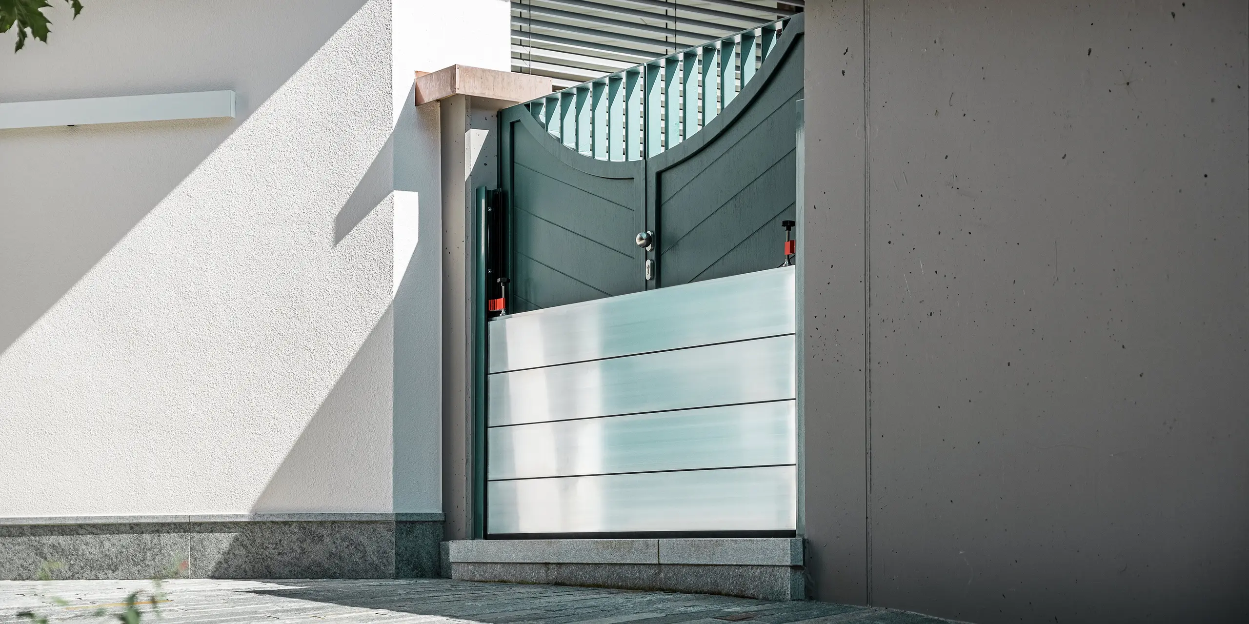 Gros plan sur un système de protection contre les crues PREFA installé sur le portail d'une maison individuelle à Schwaz, au Tyrol. Les batardeaux en aluminium sont insérés dans des profilés de fixation latéraux et protègent efficacement l'entrée des infiltrations d'eau. Ce système impressionne par sa simplicité, sa rapidité de mise en œuvre et ses matériaux résistants à la corrosion, idéal pour la protection des propriétés privées. Les profilés muraux sont de la même couleur que la porte, créant ainsi une impression d'ensemble harmonieuse.