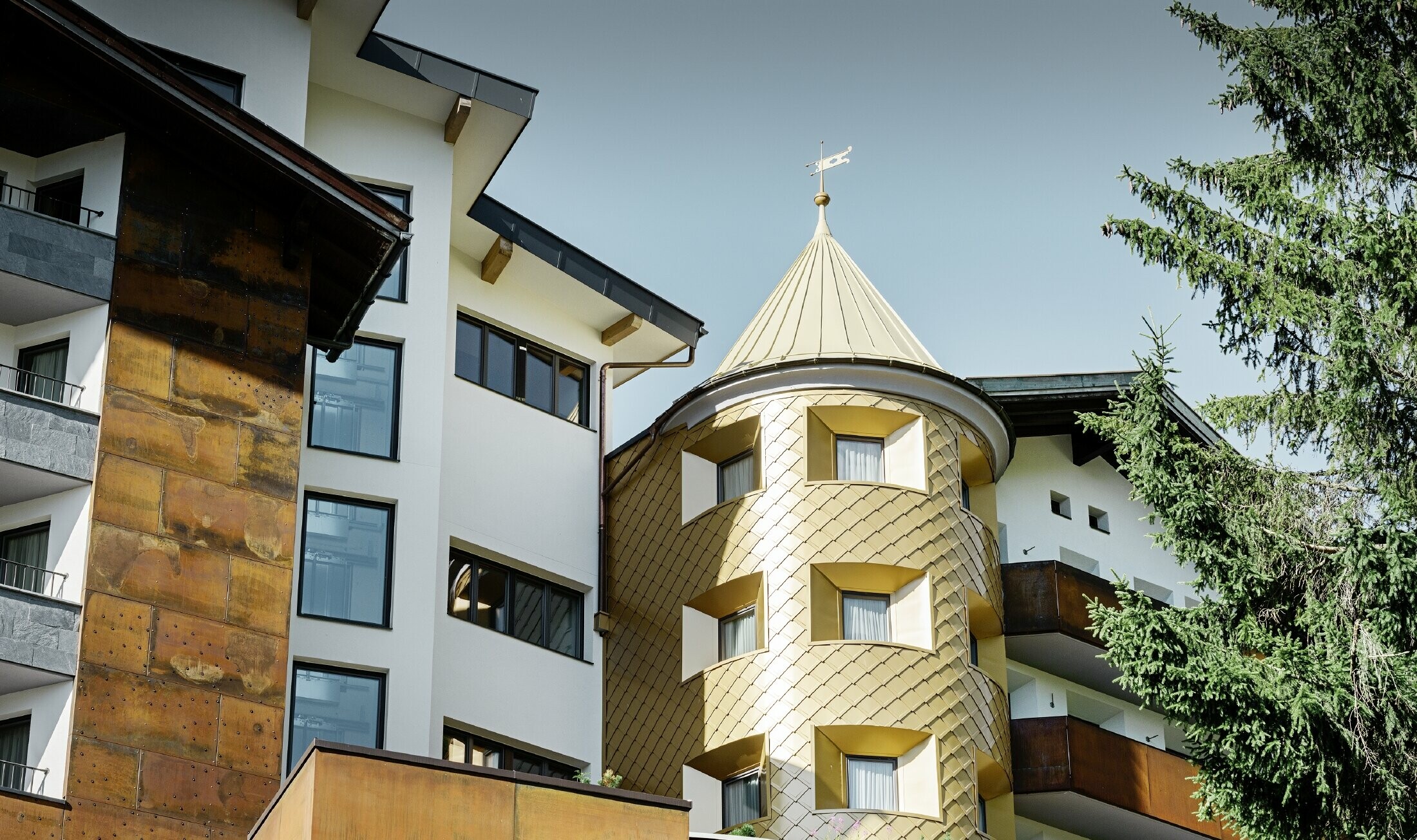 Hôtel traditionnel d’Ischgl avec balcons et façade en bois — Façade de la tour habillée de losanges en aluminium PREFA de couleur or