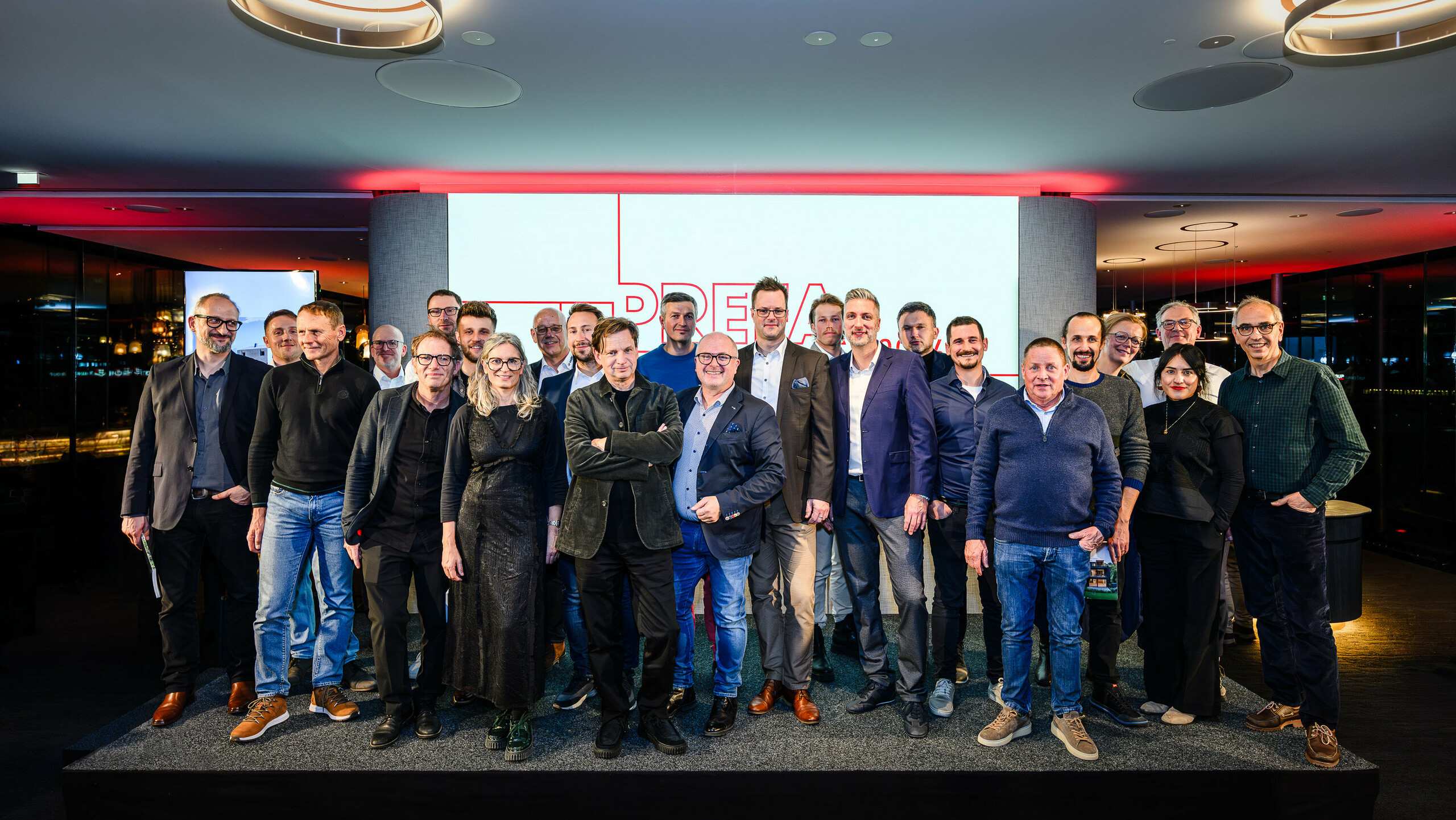Photo de groupe des architectes, urbanistes et fabricants sur la scène de la présentation PREFARENZEN 2026 au k47.wien – un symbole fort de communauté, de créativité et d'architecture d'avenir. Devant le logo PREFARENZEN illuminé se tiennent les concepteurs des projets impressionnants intégrant l'aluminium PREFA. Cette scène reflète la fierté, l'innovation et la collaboration. Les produits PREFA offrent des solutions durables et résistantes aux intempéries, au design soigné – idéales pour les concepts architecturaux modernes. Une soirée inspirante, riche en échanges, en visions et en partenariats solides.