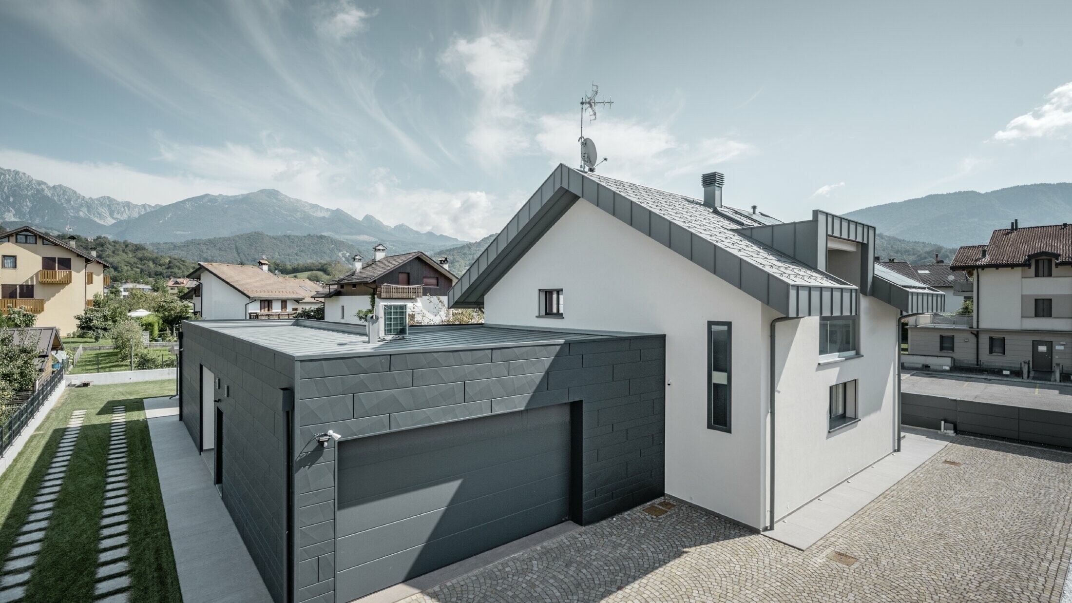 Photo de la maison individuelle, le garage est habillé de Siding.X tandis que le toit est recouvert de R.16 dans la couleur P.10 gris souris.