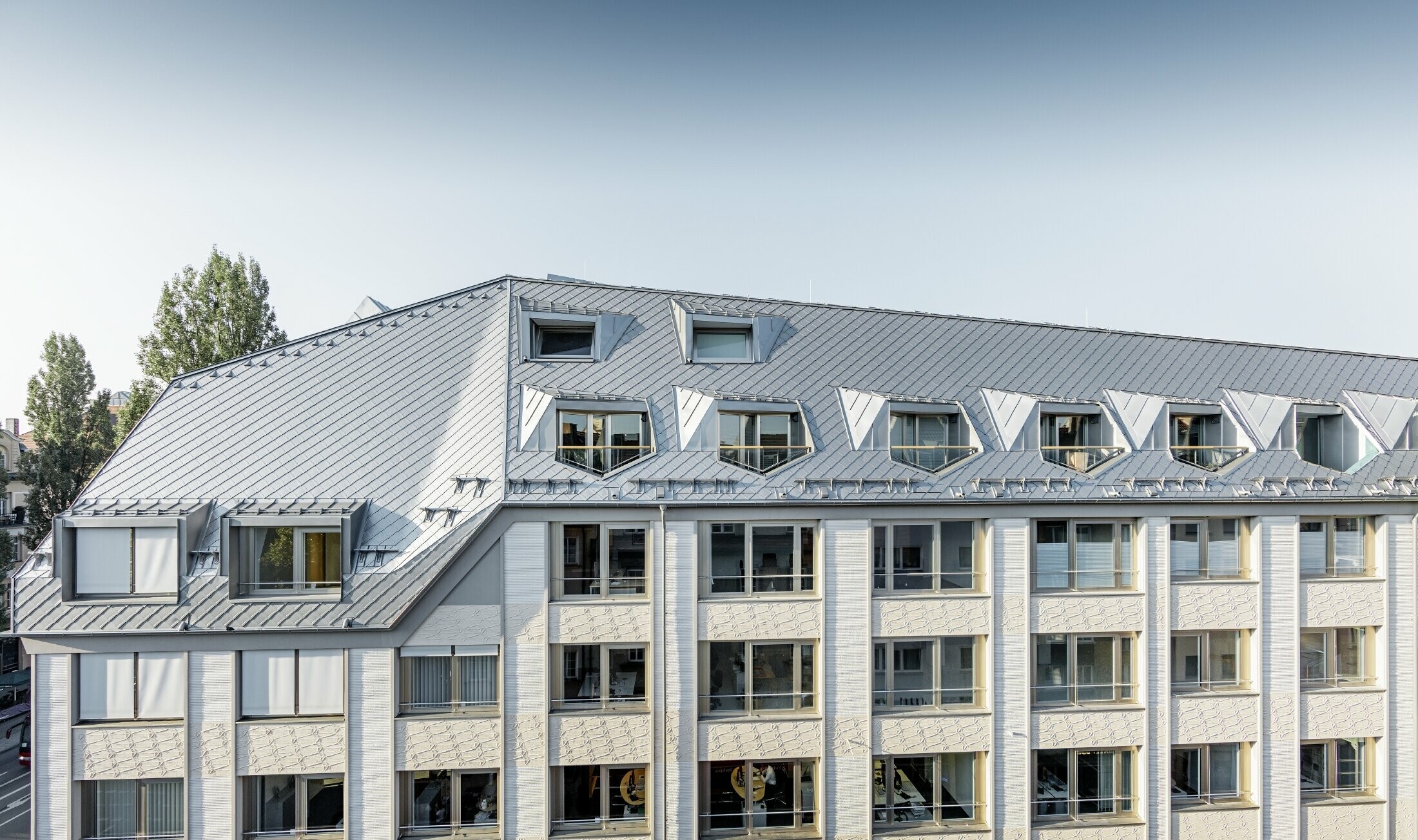 Appartements mansardés rénovés et dotés de spacieuses mezzanines, aménagés dans un immeuble d’habitation et de commerces munichois de la Leopoldstraße, à l’angle de la Hohenzollernstraße — Couverture de toit réalisée avec des losanges de toiture PREFA
