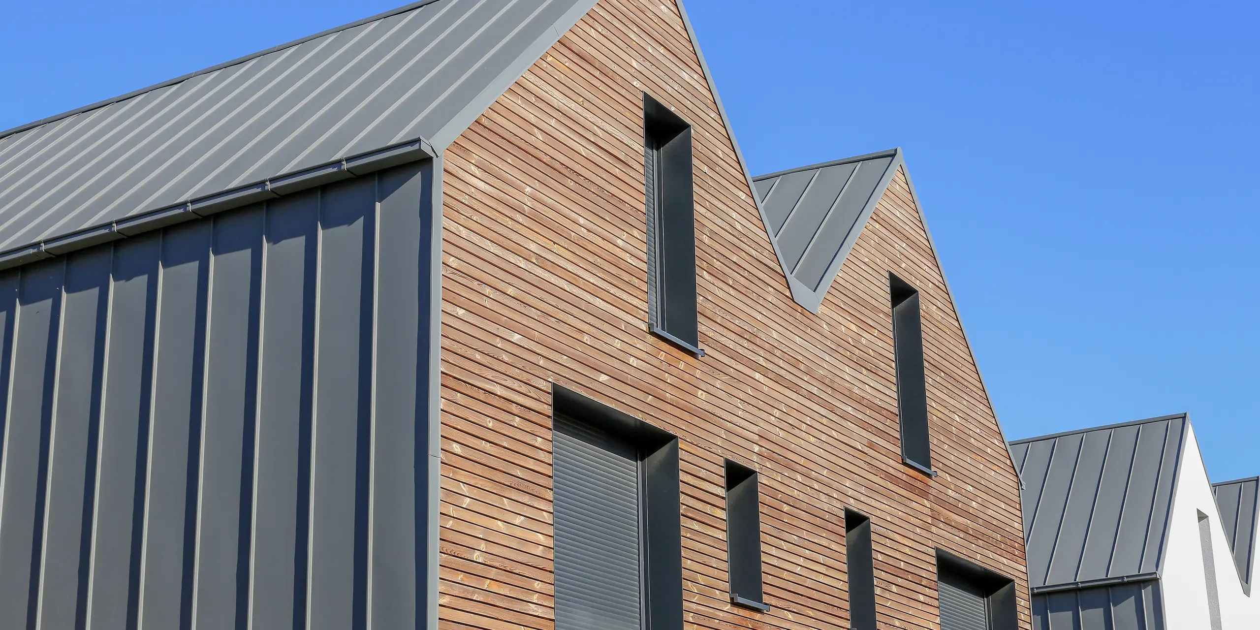 Le joint debout PREFALZ en gris souris s'étend sur les façades et les toits à pignon d'un lotissement mitoyen à Mundolsheim. Les coques uniformes du bâtiment en aluminium créent une image globale harmonieuse.