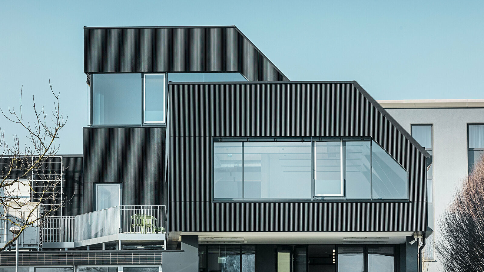Vue latérale du bâtiment du café Amann par une journée ensoleillée. Un profil ondulé noir a été utilisé pour protéger le bâtiment.