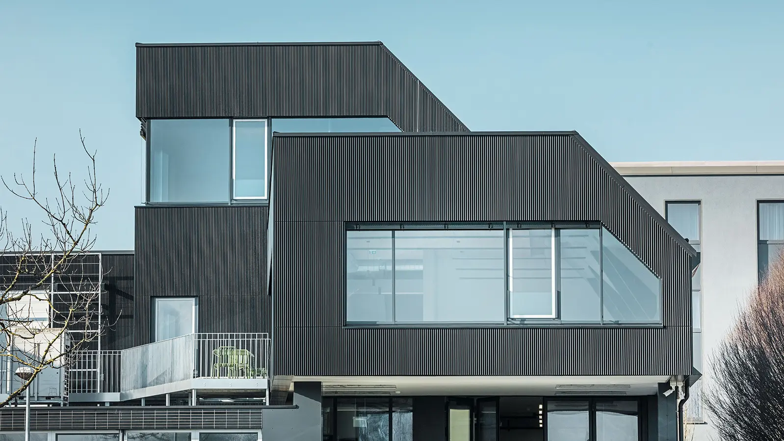 Vue latérale du bâtiment du café Amann par une journée ensoleillée. Un profil ondulé noir a été utilisé pour protéger le bâtiment.