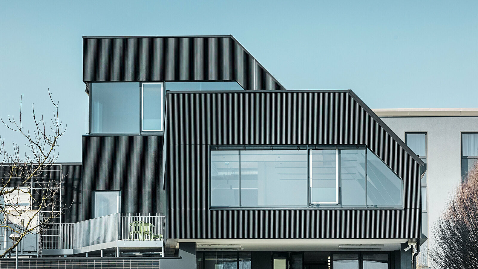 Vue latérale du bâtiment du café Amann par une journée ensoleillée. Un profil ondulé noir a été utilisé pour protéger le bâtiment.