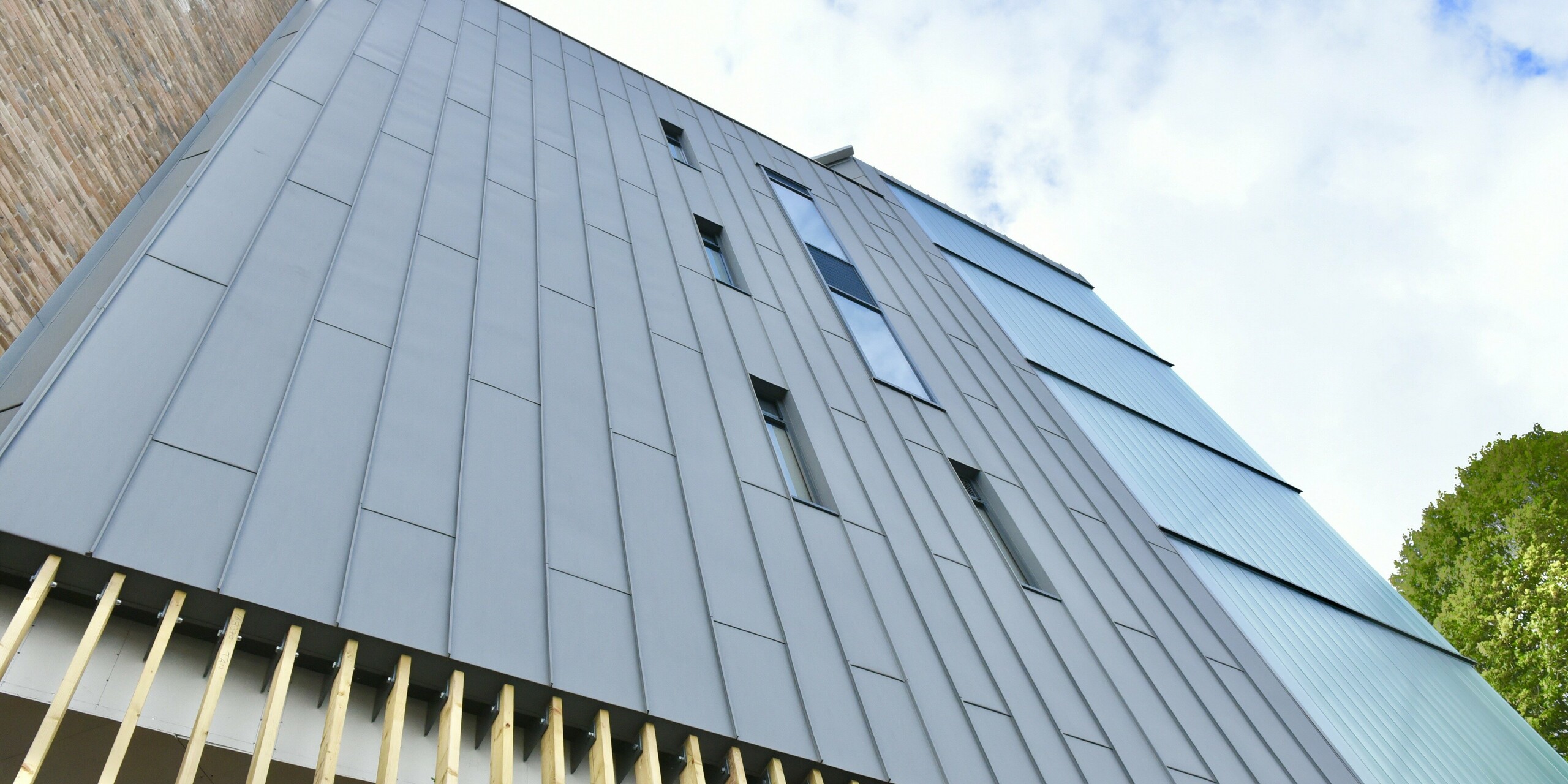 Vue détaillée du bardage à joint debout PREFALZ en gris quartz au North Regional College. Le traitement précis de l'aluminium souligne le caractère durable et moderne de la façade, qui s'intègre harmonieusement dans l'architecture globale.