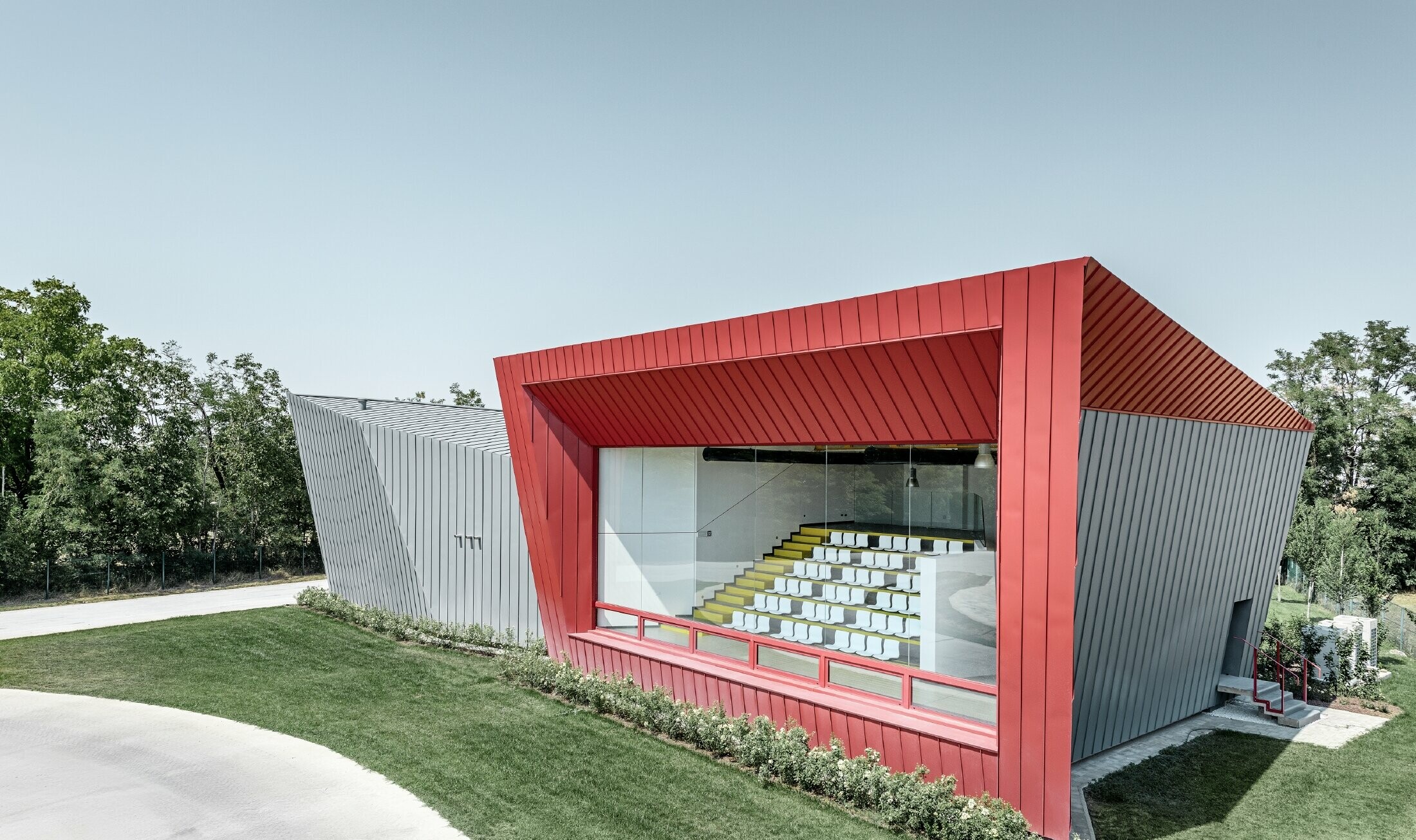 Centre d’entraînement moderne Dieci à Montecchio Emilia (Italie) — Façade des tribunes en aluminium réalisée avec des bandes Prefalz gris souris et Falzonal rouge carmin