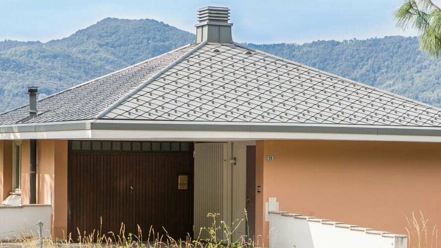 Bâtiment d’habitation orange avec toit en pavillon couvert de losanges de toiture 29 × 29 PREFA couleur P.10 gris souris.