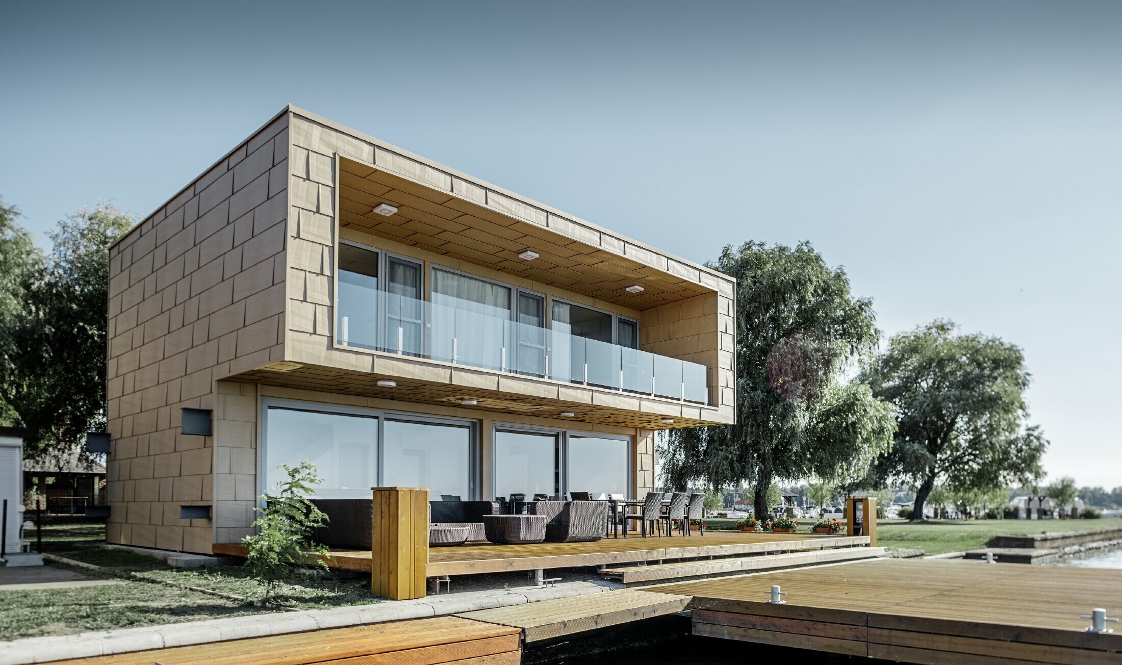 Maison secondaire moderne au toit plat et aux grandes baies vitrées donnant sur le lac — Façades en aluminium PREFA de couleur brun sable aux arêtes prononcées