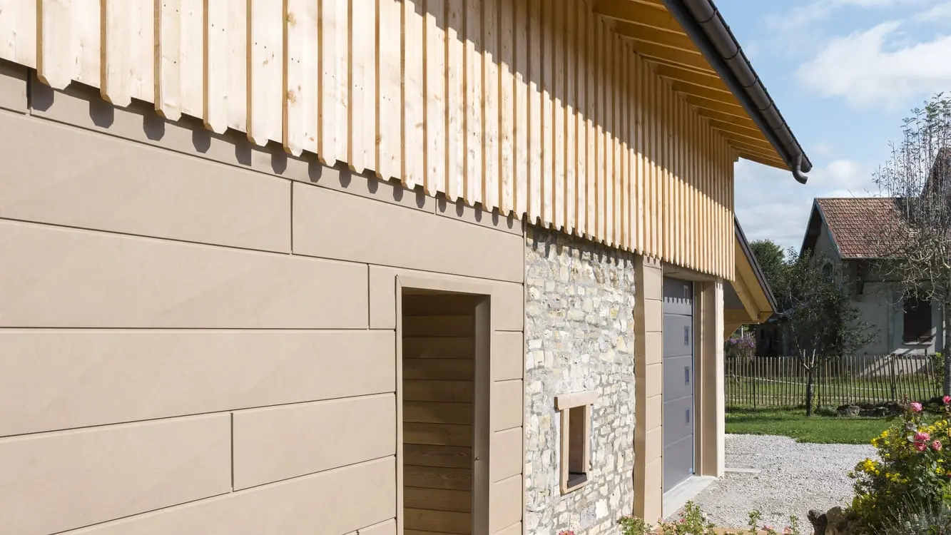 Photo de côté de la maison individuelle où on aperçoit les Siding.X PREFA dans la teinte P.10 brun sable associés à un pignon en bois