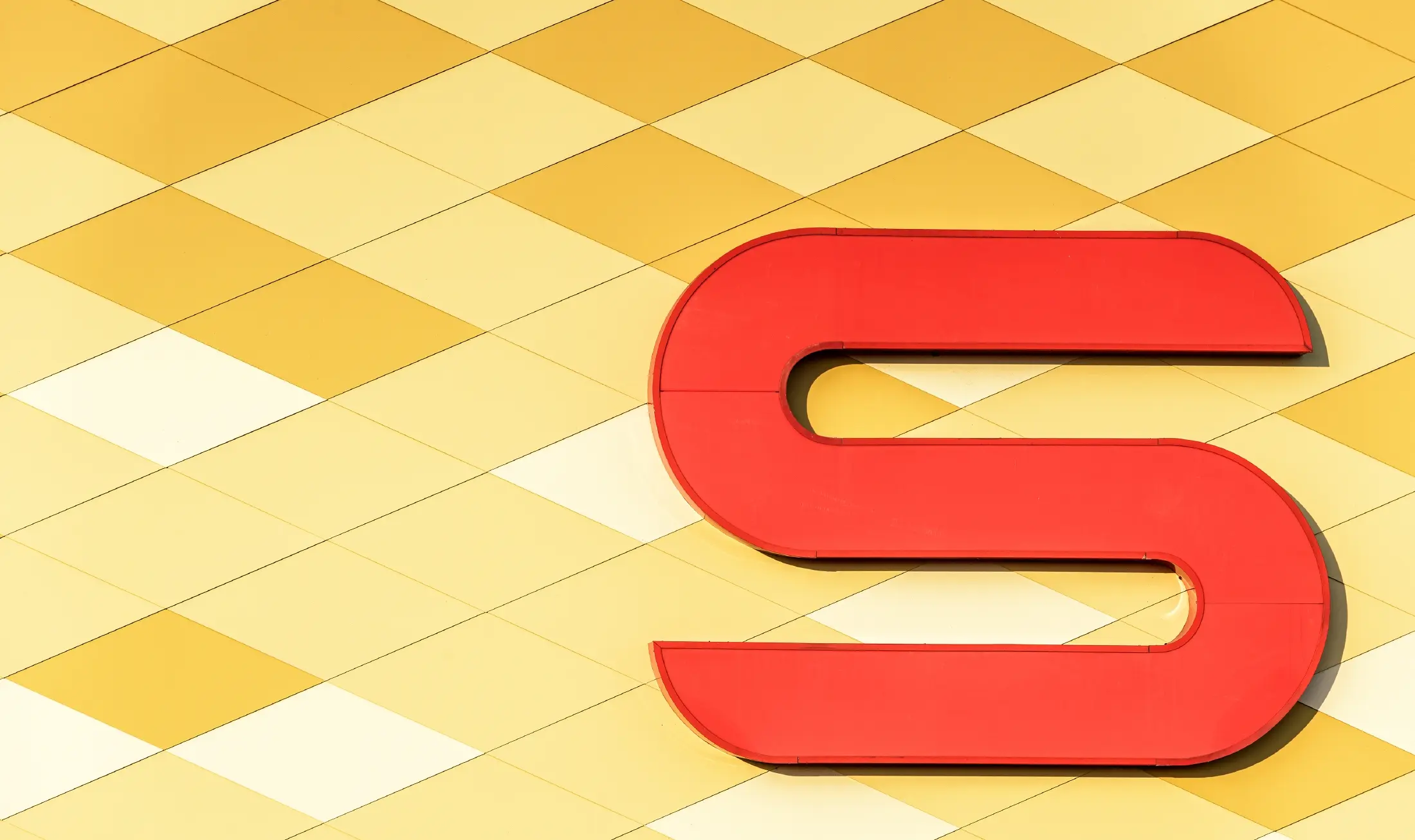 Magasin Spar — Façade en aluminium PREFA habillée de losanges jaune pâle à orange et arborant le logo Spar