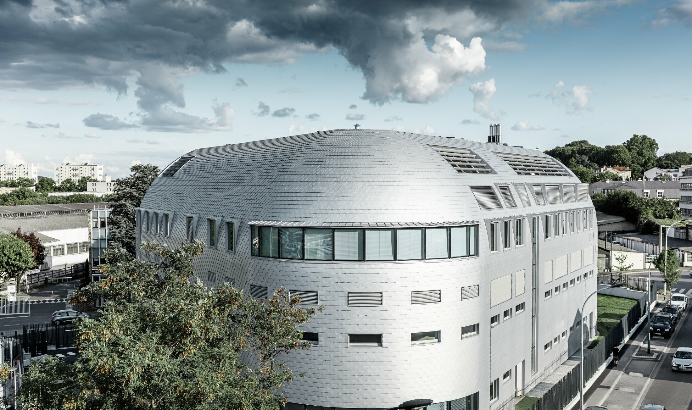 Bâtiment de société avec dôme arrondi et habillé de bardeaux en alu PREFA couleur argent métallisé ;