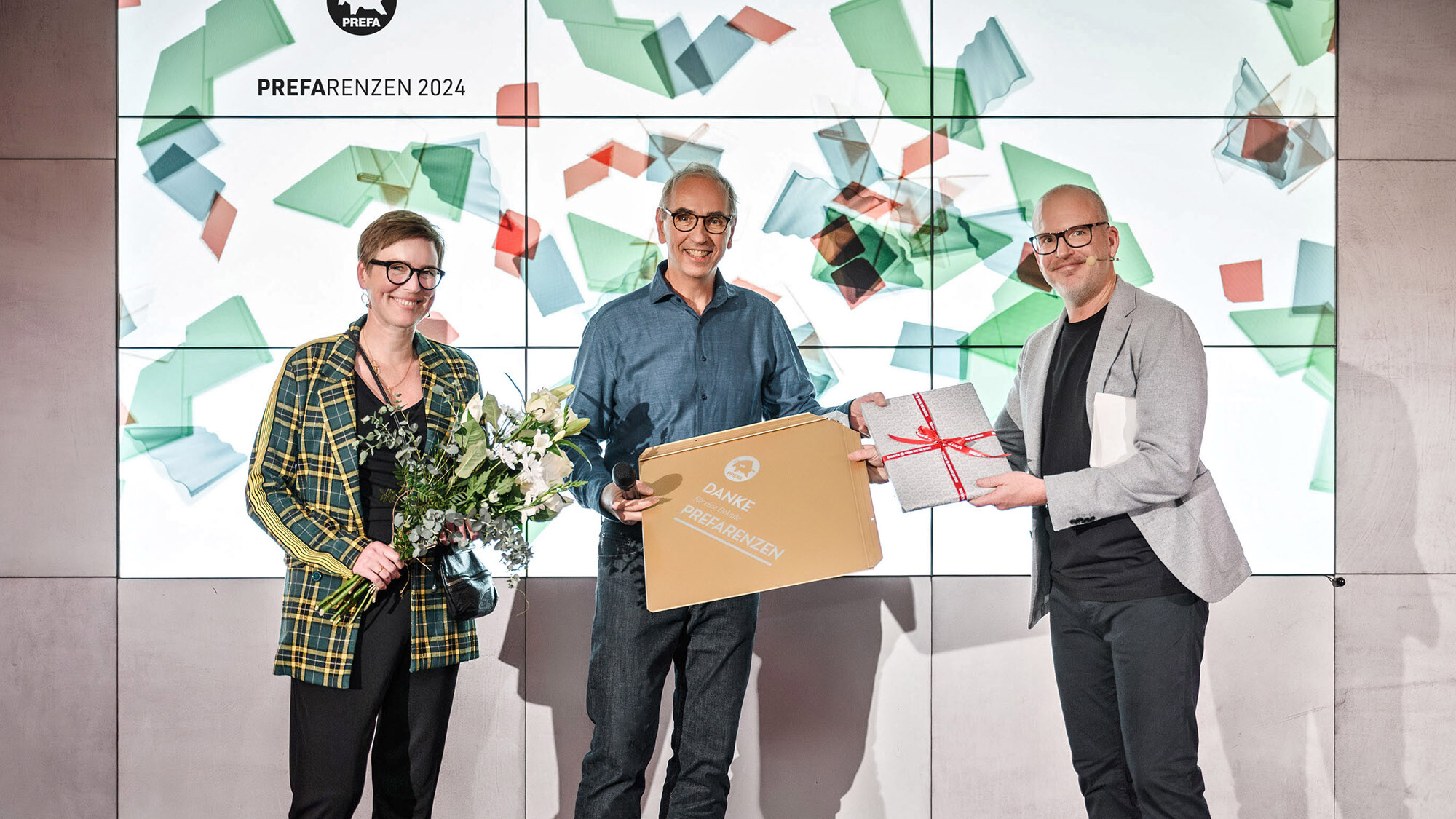Les photographes Juliane Croce et Wolfgang Croce avec le directeur marketing international Jürgen Jungmair lors de la remise d'un cadeau devant l'espace de présentation