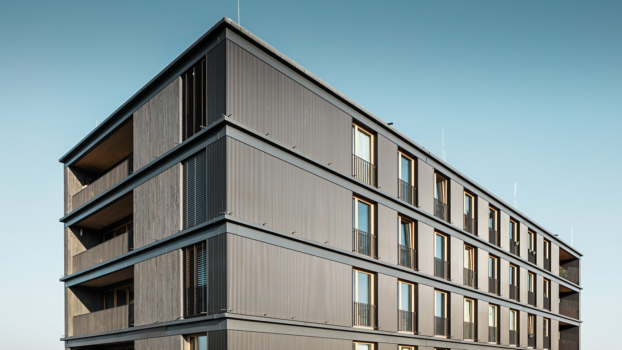  L'immeuble d'habitation et de bureaux vu de côté : le profil ondulé de PREFA et la façade en bois sont presque indiscernables.