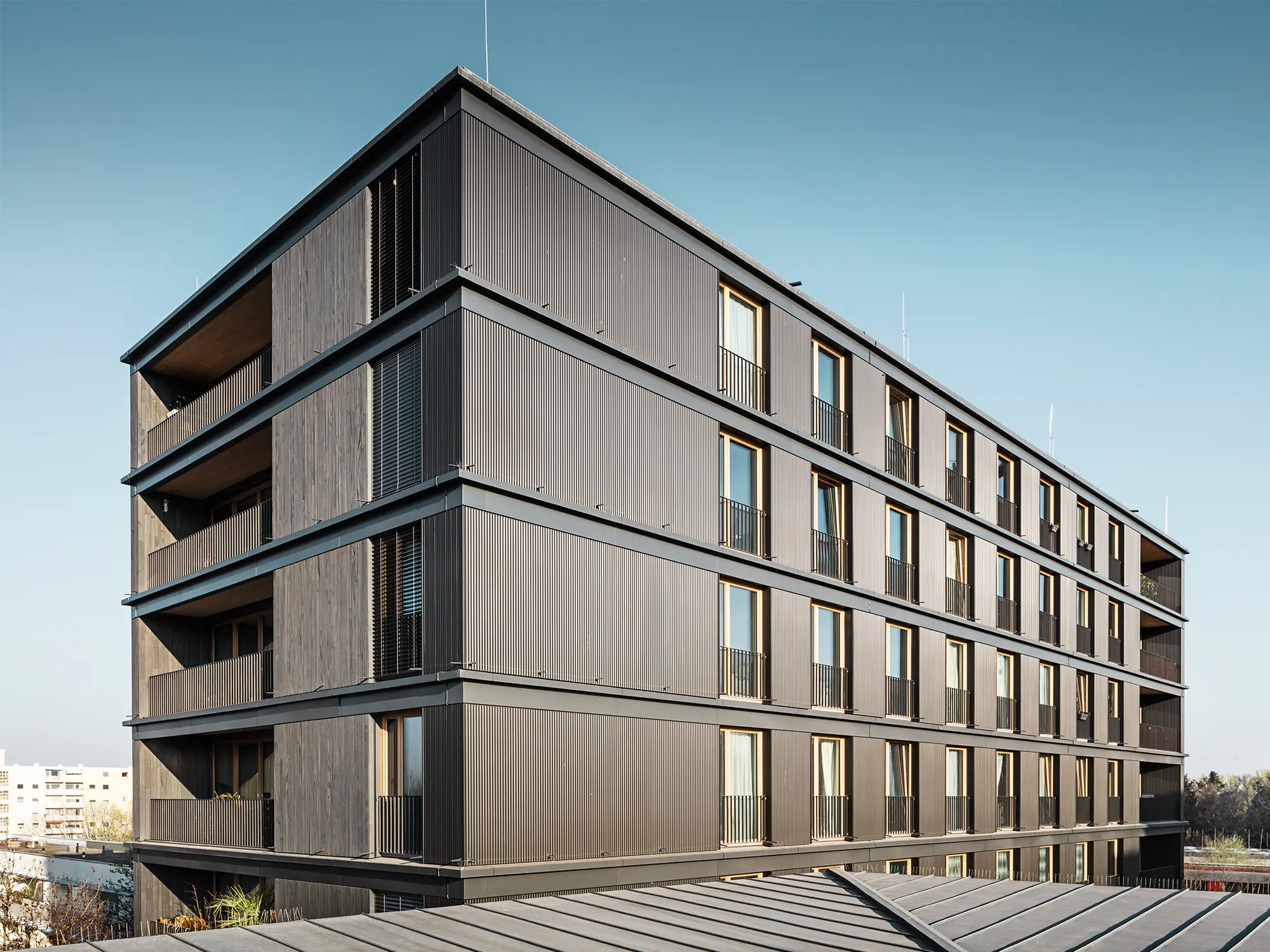 L'immeuble d'habitation et de bureaux vu de côté : le profil ondulé de PREFA et la façade en bois sont presque indiscernables.