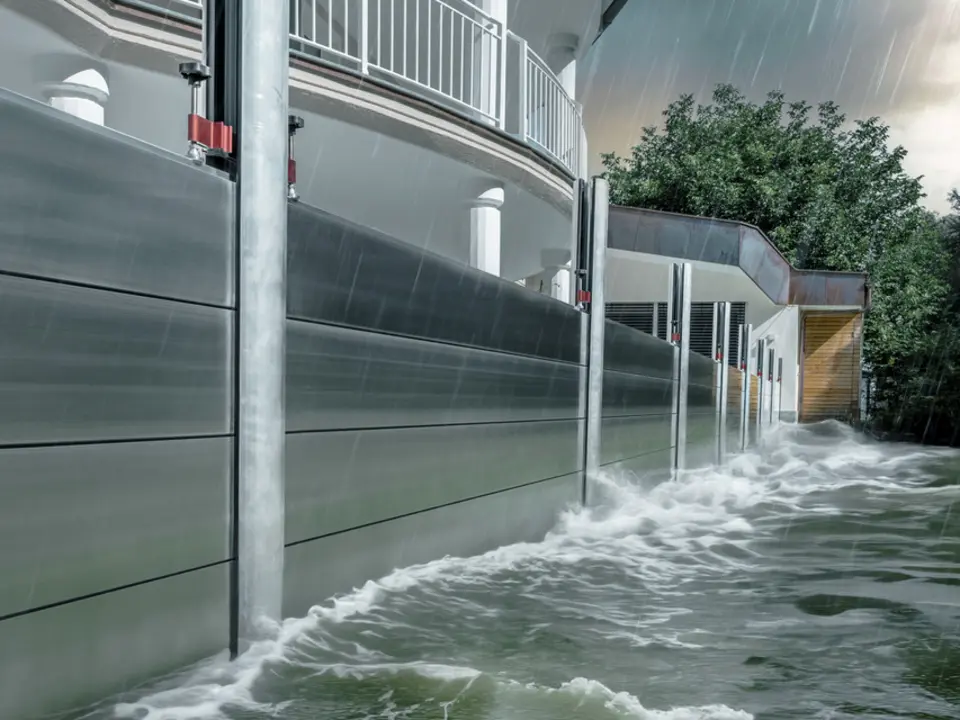 Gros plan sur la protection contre les crues PREFA en aluminium, qui résiste toujours aux inondations catastrophiques et protège la maison individuelle en arrière-plan.