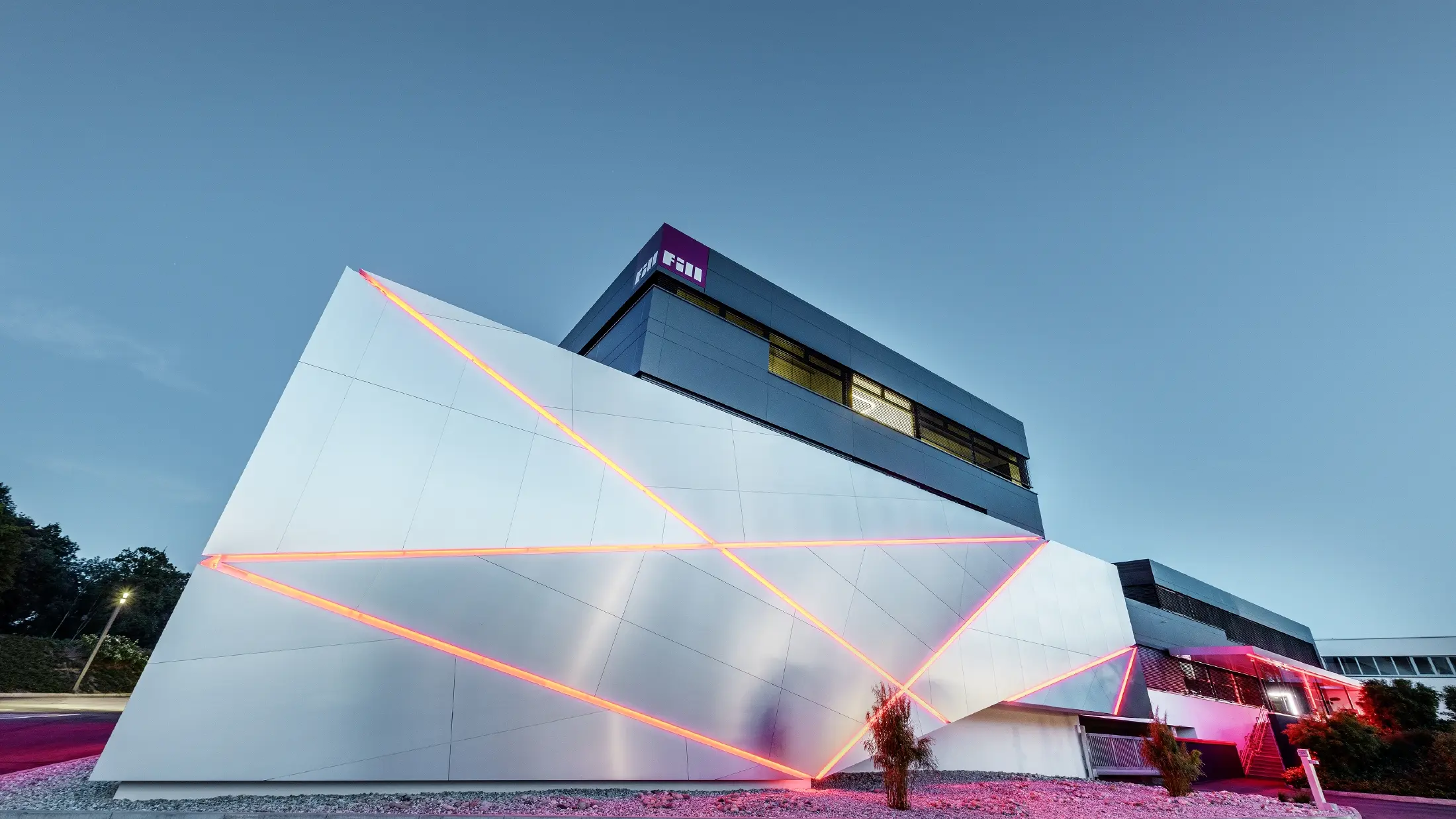 Bâtiment d’entreprise de la société Fill — Façade futuriste aux joints rétroéclairés réalisée avec des panneaux composites PREFA en aluminium brossé