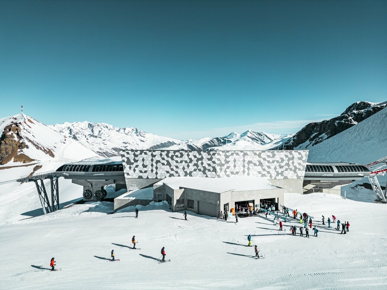 Vue d'une des stations du nouveau téléphérique Le Jandri de la station Les 2 Alpes, recouverte de panneaux composites en aluminium PREFABOND façonné en losanges de trois couleurs différentes : blanc Prefa, blanc pur et argent fumé.