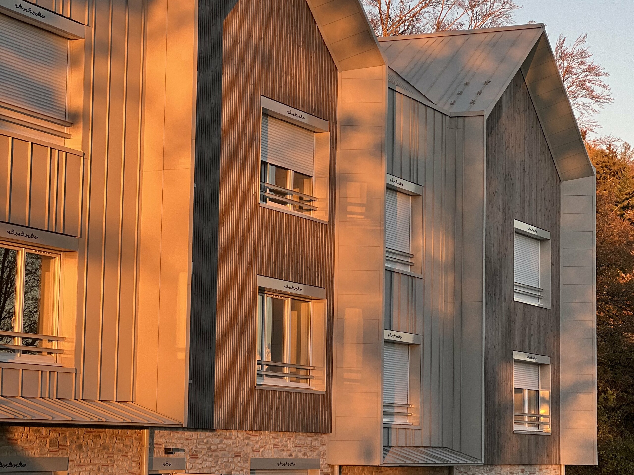 Prise de vue d'ensemble du complexe résidentiel attenant au Château des Avenières dont la façade et la toiture sont couvertes de joint debout PREFALZ dans la teinte spéciale Dune.