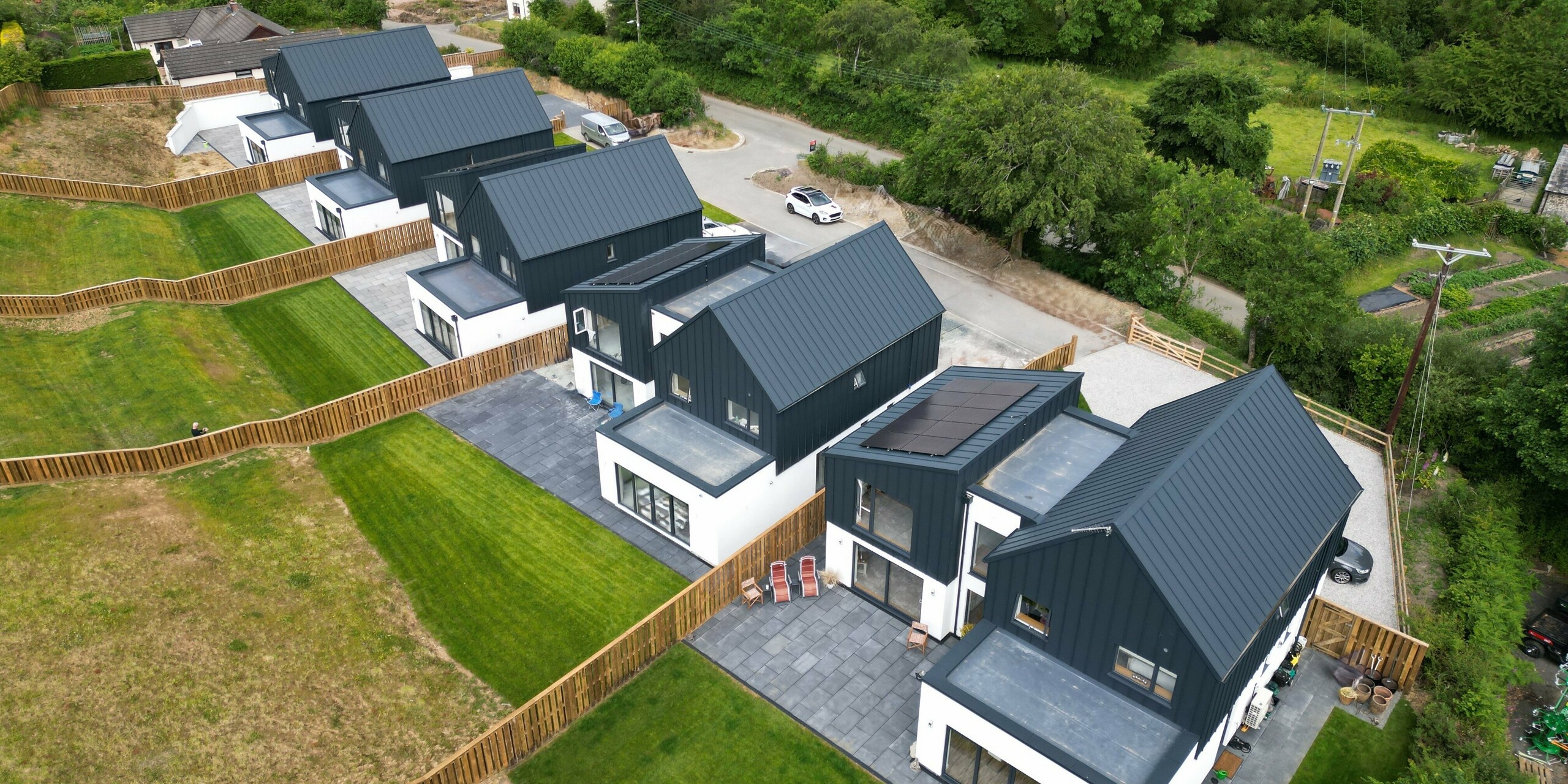 Vue aérienne d'un ensemble immobilier à Bridgerule, Devon, avec PREFALZ P.10 anthracite comme matériau de toiture et de façade uniforme. La toiture à joint debout en tôle de haute qualité et durable offre une solution résistante aux tempêtes et esthétique pour environ 1 250 m².