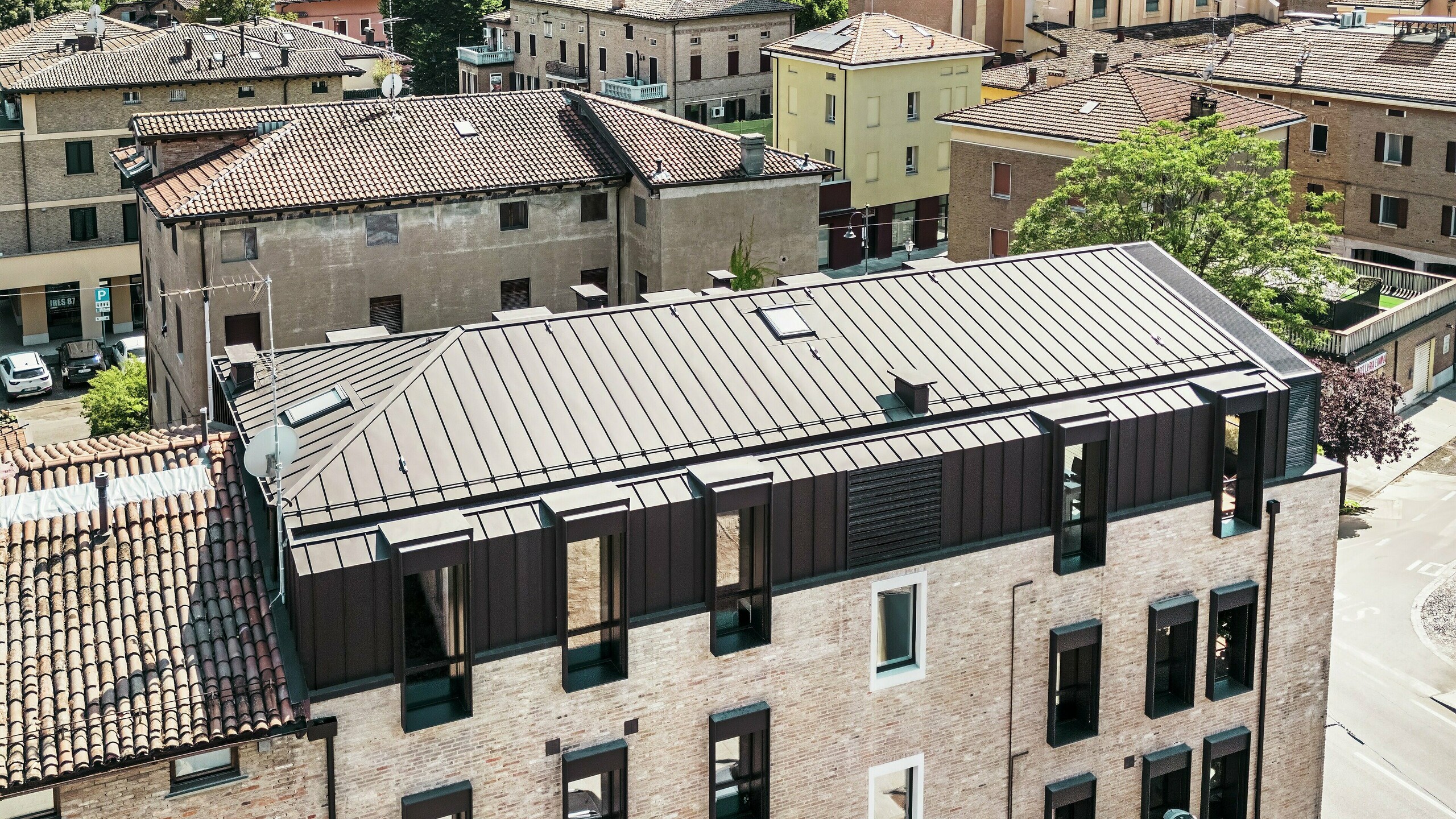 Maison en briques modernisée en Italie avec toiture en aluminium PREFALZ couleur P.10 brun noisette – alliance esthétique entre l'architecture traditionnelle en briques et une solution de toiture moderne et durable.