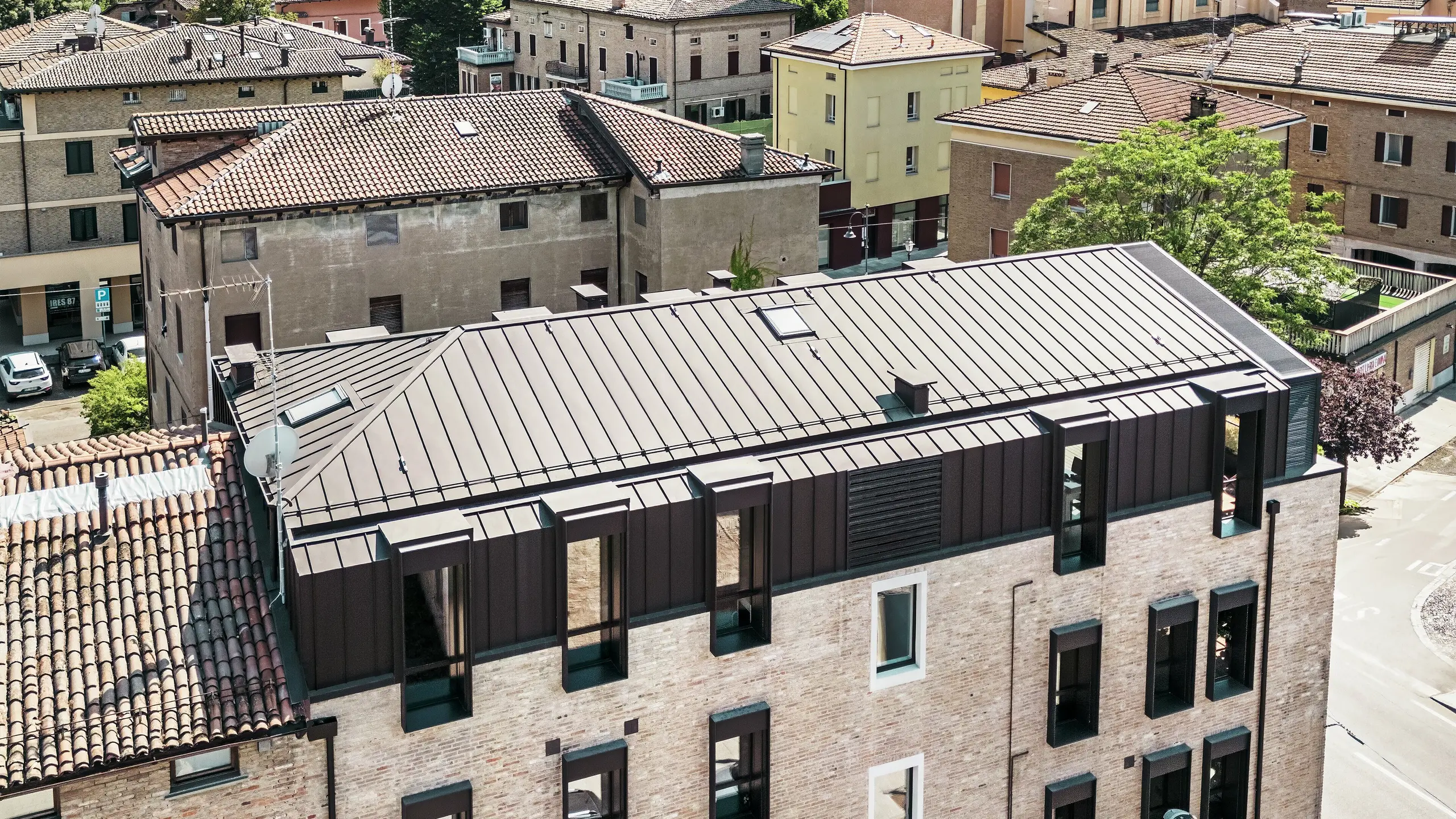 Maison en briques modernisée en Italie avec toiture en aluminium PREFALZ couleur P.10 brun noisette – alliance esthétique entre l'architecture traditionnelle en briques et une solution de toiture moderne et durable.
