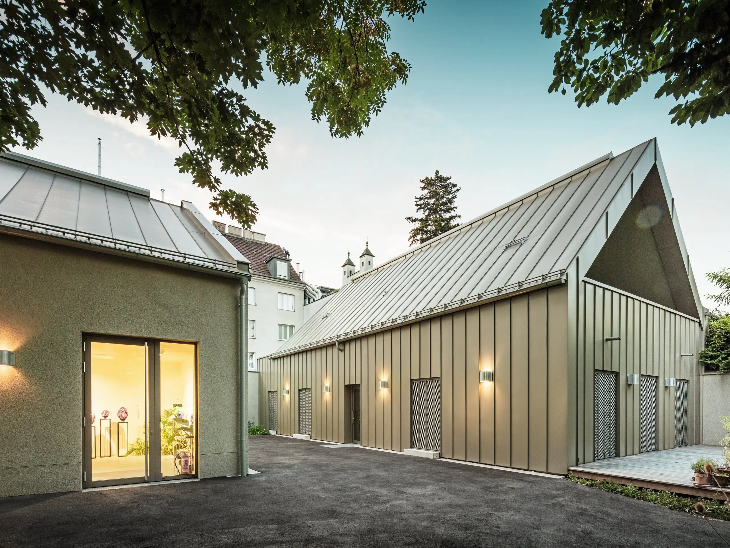 Vue latérale du Studio Comploj à Vienne avec une façade en aluminium PREFALZ en P.10 bronze Prefa. L'ensemble moderne composé d'un atelier de soufflage de verre, d'une galerie et d'un espace de vie allie artisanat et architecture.