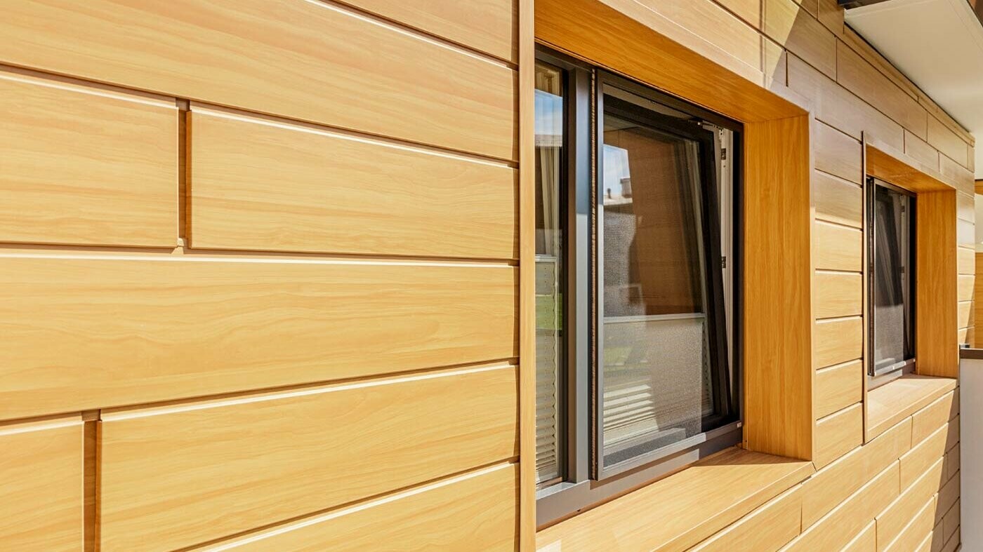 Surface de façade en aluminium avec les Sidings PREFA en aspect bois avec encadrement de fenêtre ;