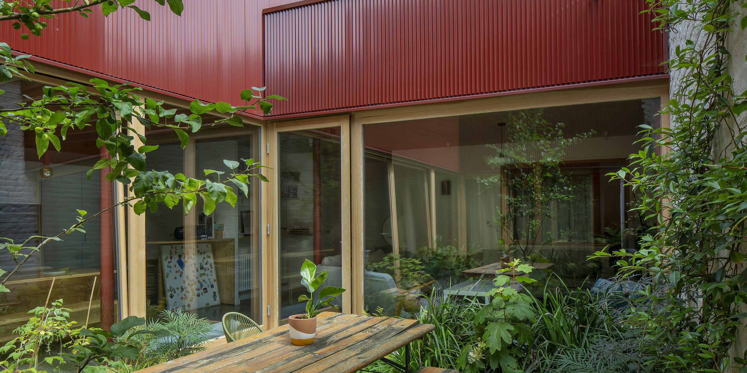 Un havre de paix à Lille : le profil rouge en zigzag de la façade donnant sur la cour intérieure structure l’espace d’une verticalité dynamique. De larges baies vitrées ouvrent la cour sur la verdure et laissent entrer abondamment la lumière. L’alliance de l’aluminium, du bois et du verre offre un rendu à la fois moderne et haut de gamme, tout en étant extrêmement facile d’entretien.