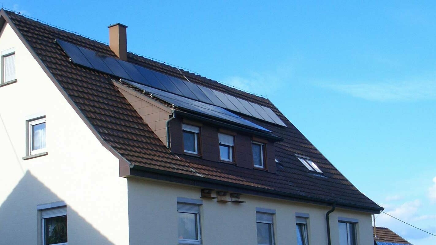 Maison individuelle avec toit en tuiles nécessitant une rénovation. Le toit est pourvu d’une lucarne ainsi que d’une installation photovoltaïque.