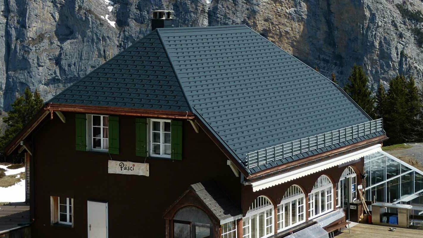 Rénovation de la toiture à deux pans en croupe d’un refuge de montagne, à l’aide de bardeaux de toiture PREFA et arrêts de neige