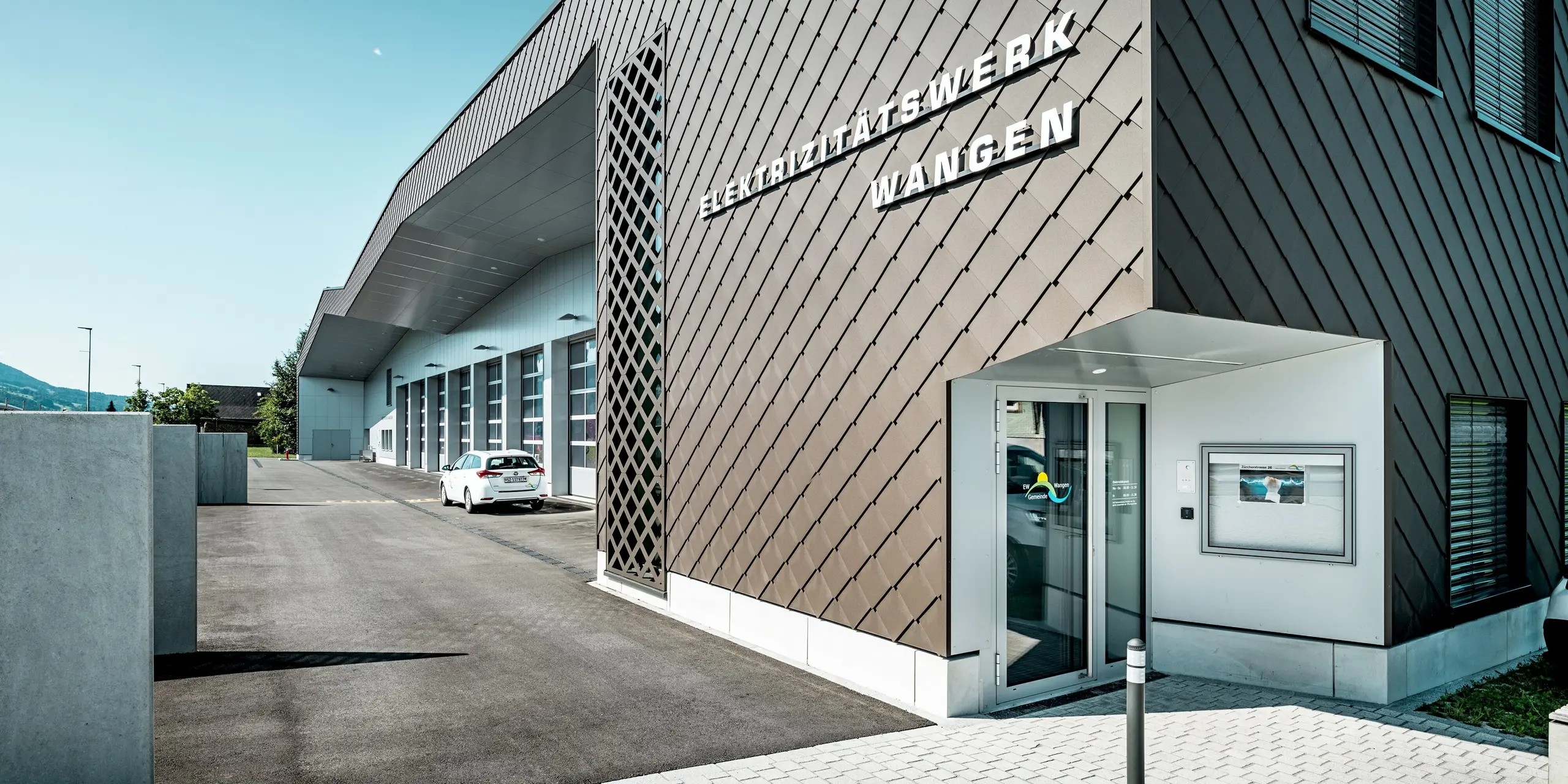 Vue saisissante de la façade de la centrale électrique et de la caserne de pompiers de Wangen, en Suisse. Les losanges PREFA 29 x 29 en P.10 Brun, avec leur motif en losange précis, confèrent au bâtiment une profondeur exceptionnelle. Les panneaux composites en aluminium clair Prefa Blanc apportent une touche de modernité. Les façades en aluminium, d'une grande durabilité, impressionnent par leur résistance aux intempéries, leur faible besoin d'entretien et leur architecture expressive.