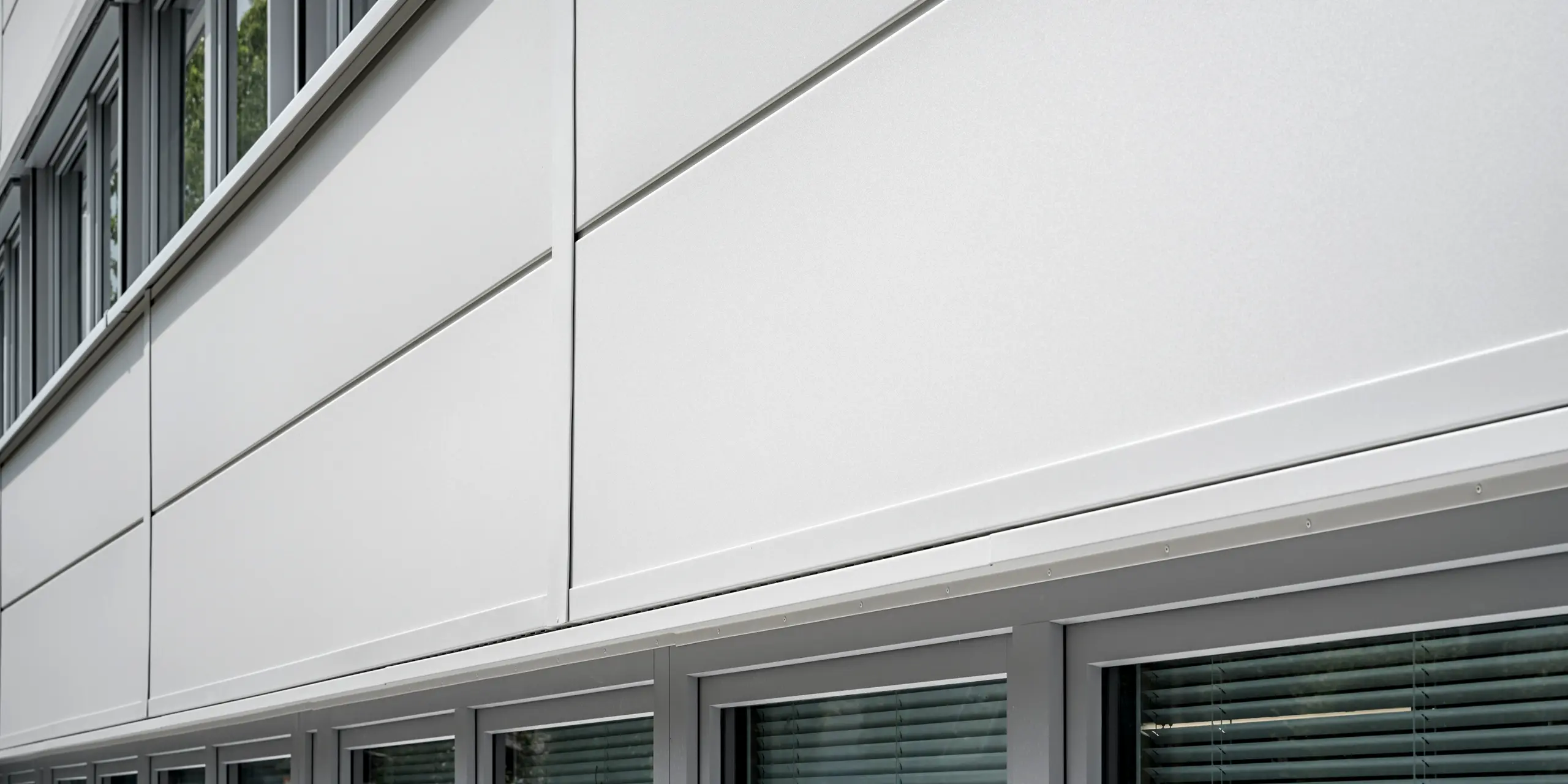 Des Sidings PREFA grand format entourent un bâtiment d'entreprise à Oberschleißheim (Allemagne). Les éléments de façade extra-larges en aluminium ont été choisis dans la couleur blanc Prefa.