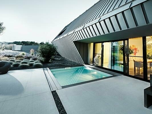 Modernes Gebäude mit Terrasse und Pool, eingedeckt mit Prefalz Aluminium Elementen von PREFA