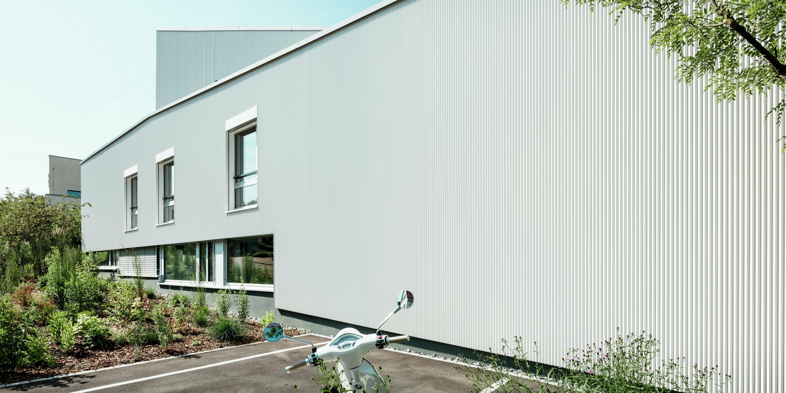Des lignes épurées et un design minimaliste caractérisent la façade des mini-maisons du Zollikerberg, qui arbore des profilés dentelés PREFA et des panneaux composites en aluminium blanc pur P.10. Les fines dentelures créent un jeu de lumière saisissant, tandis que l'aluminium durable assure une protection optimale contre les intempéries. Le style moderne est accentué par le nombre réduit de fenêtres et l'élégant alignement des surfaces.