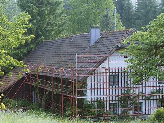Ancienne toiture de la maison traditionnelle « Wiesenhaus » peu avant sa rénovation avec des bardeaux PREFA (échafaudage en place)