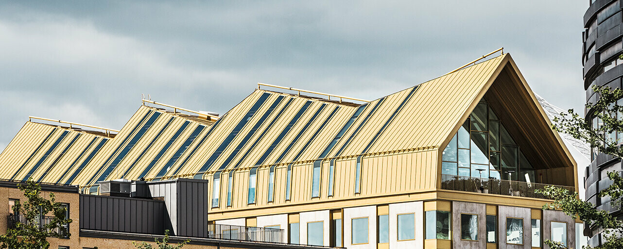 Vue latérale du bâtiment à Malmö, revêtu grâce au système de toiture PREALZ dans la teinte spéciale Jaisalmer Gold.