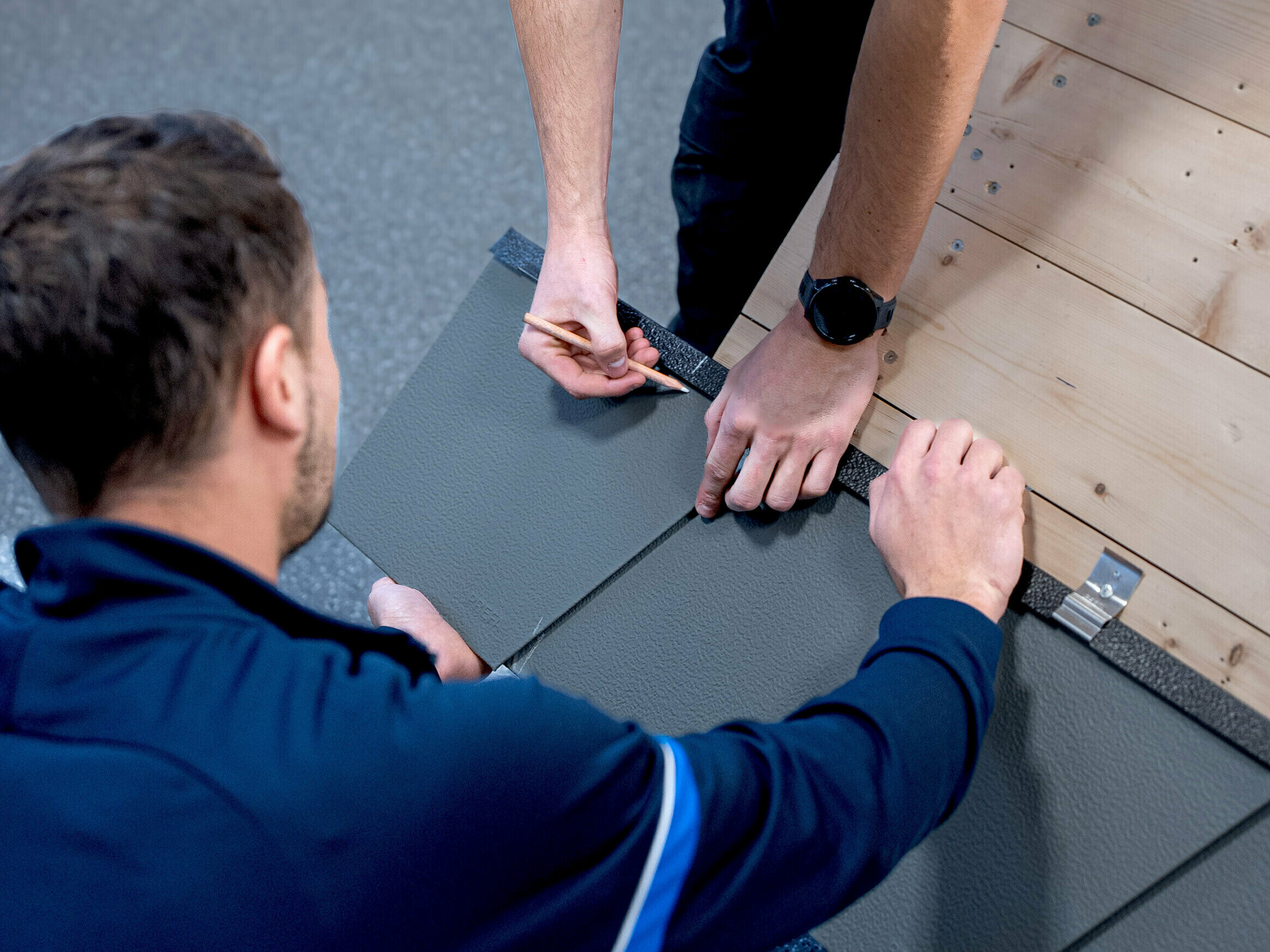 Le formateur PREFA montre aux participants comment poser correctement les produits PREFA lors des PREFA Academy.