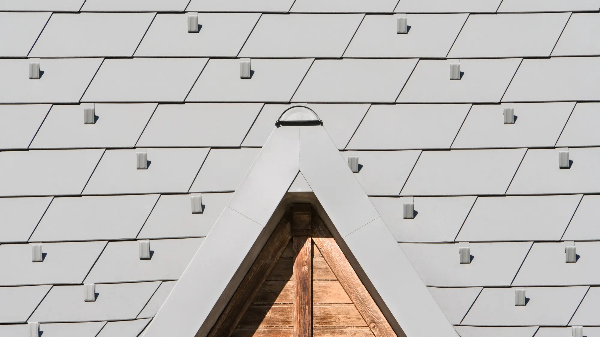 Zoom sur les détails de lucarnes en aluminium PREFA. On aperçoit la nouvelle toiture en bardeau PREFA dans la teinte P.10 gris souris stucco