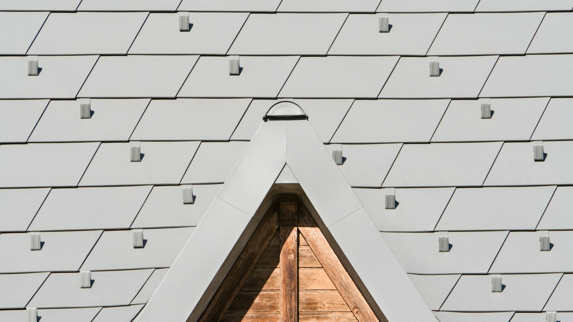 Zoom sur les détails de lucarnes en aluminium PREFA. On aperçoit la nouvelle toiture en bardeau PREFA dans la teinte P.10 gris souris stucco