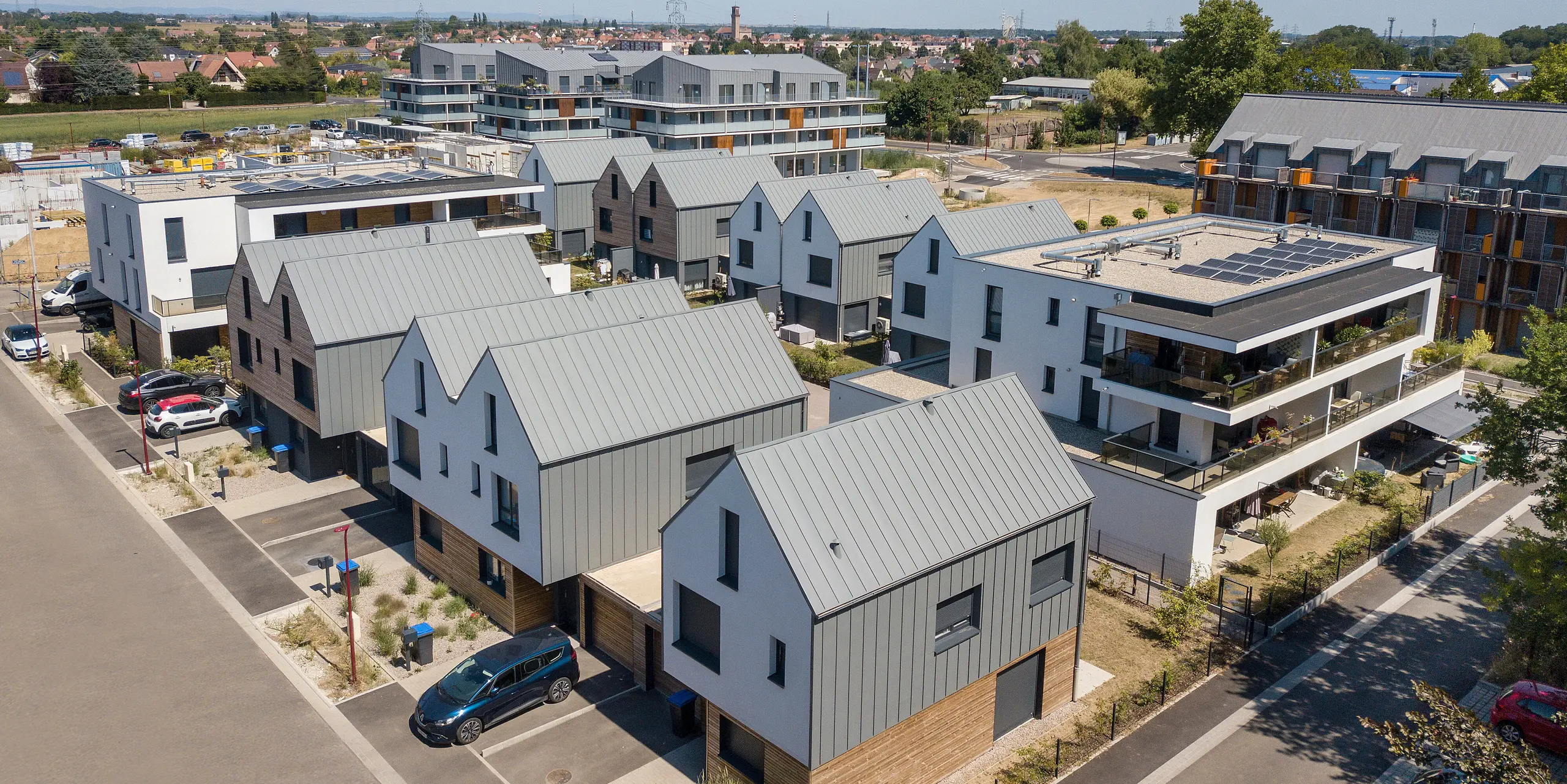 Le joint debout PREFALZ en gris souris s'étend sur les façades et les toits à pignon d'un lotissement mitoyen à Mundolsheim. Les coques uniformes du bâtiment en aluminium créent une image globale harmonieuse.